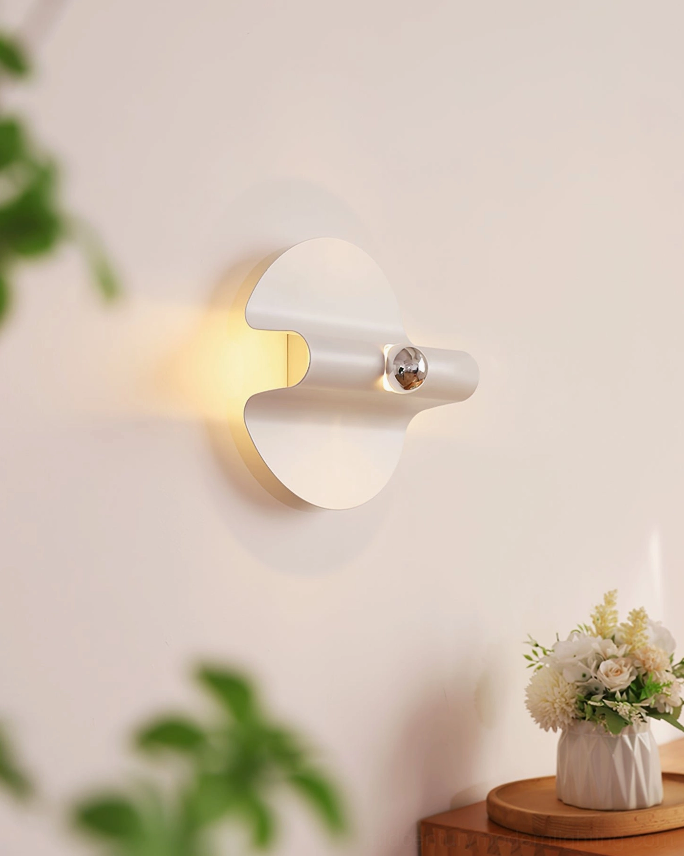 Modern minimalist wall sconce with matte white circular base and polished chrome fixture hardware