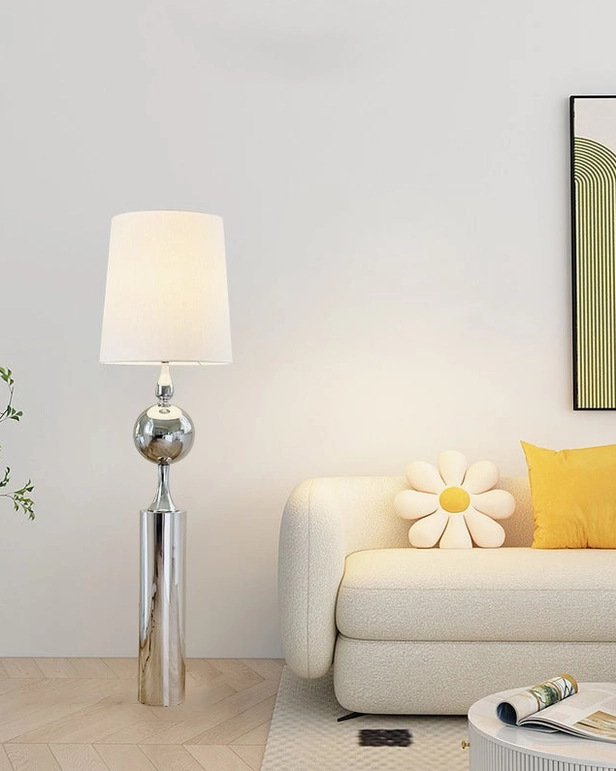 Sculptural silver floor lamp in minimalist living room with sofa, throw pillows, and wall artwork - modern aesthetic
