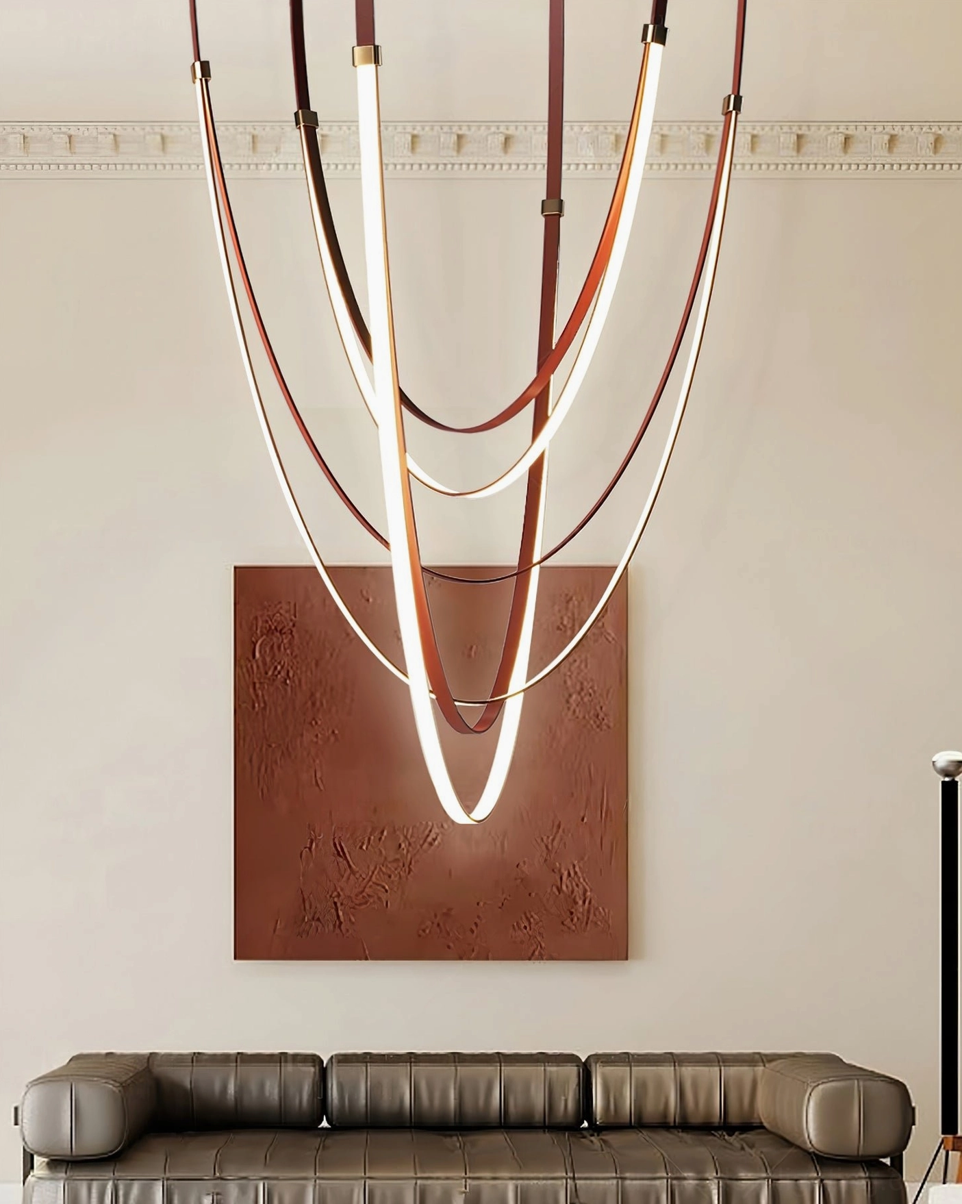Sculptural curved pendant light suspended in luxury modern living room with leather sofa, warm gold accents and artistic wall decor