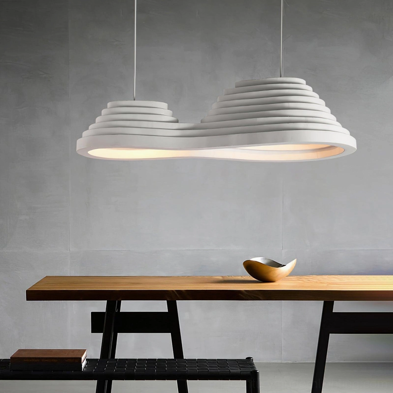 Low angle view of wavy pendant light fixture in industrial wooden dining space with wabi-sabi aesthetic