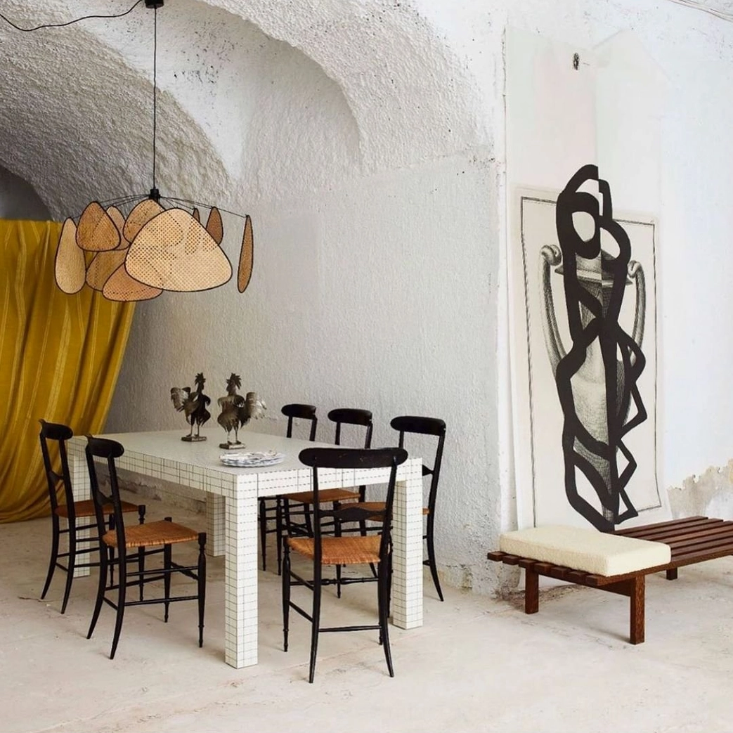 Sculptural rattan pendant light in rustic minimalist dining space, rounded organic shades in warm tan, artistic wall backdrop