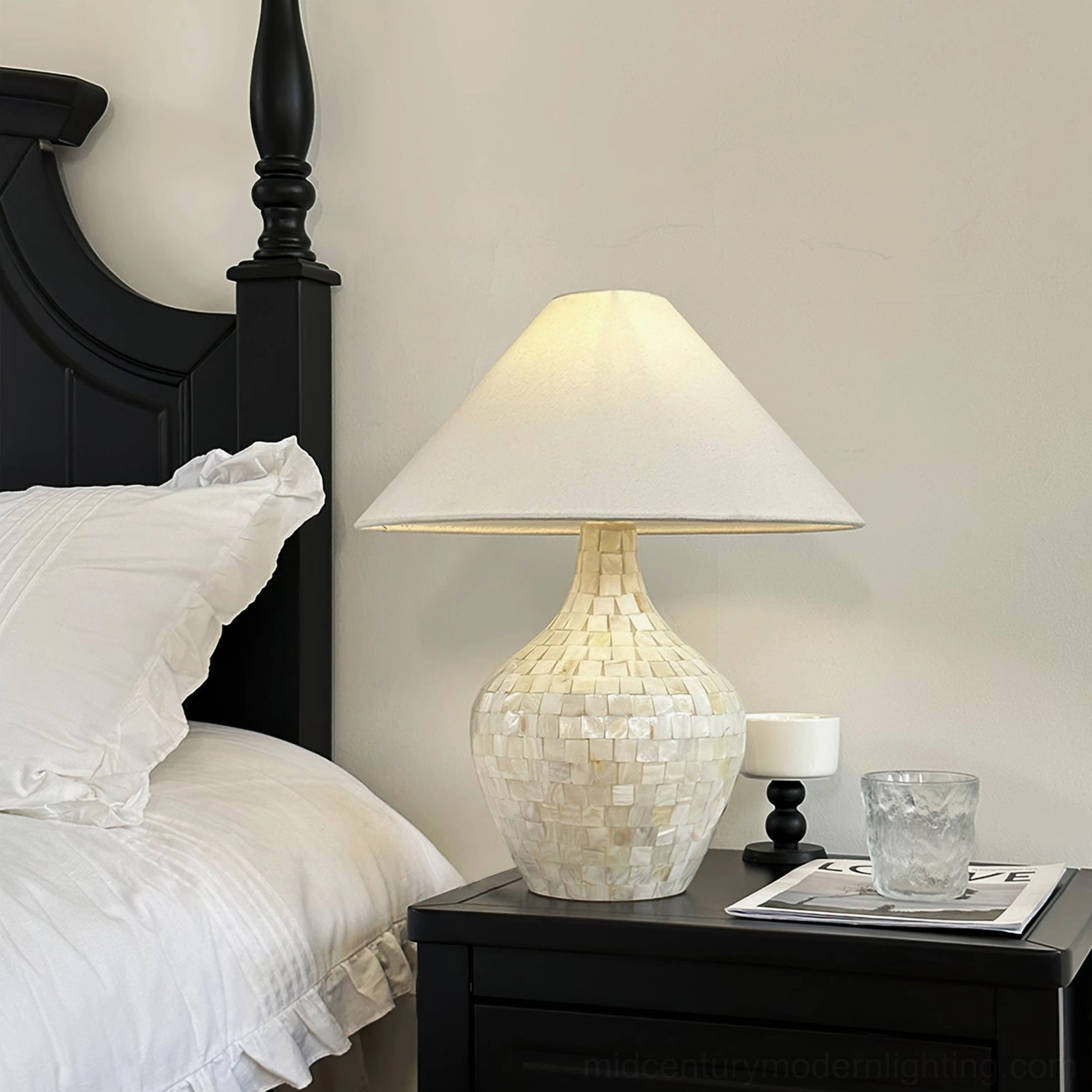 Seashell mosaic lamp on black nightstand in master bedroom with linen bedding, warm ambient bedside lighting