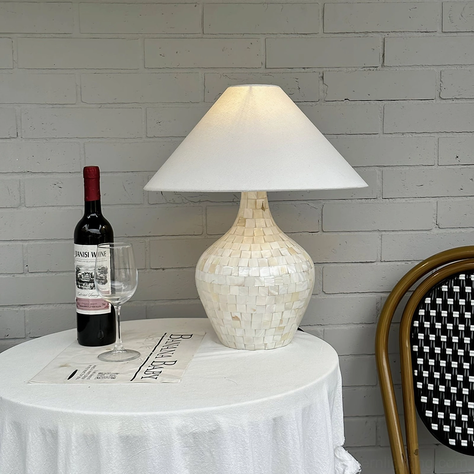Seashell inlay table lamp on small round cafe dining table with wine set and rattan chair, bistro ambiance lighting