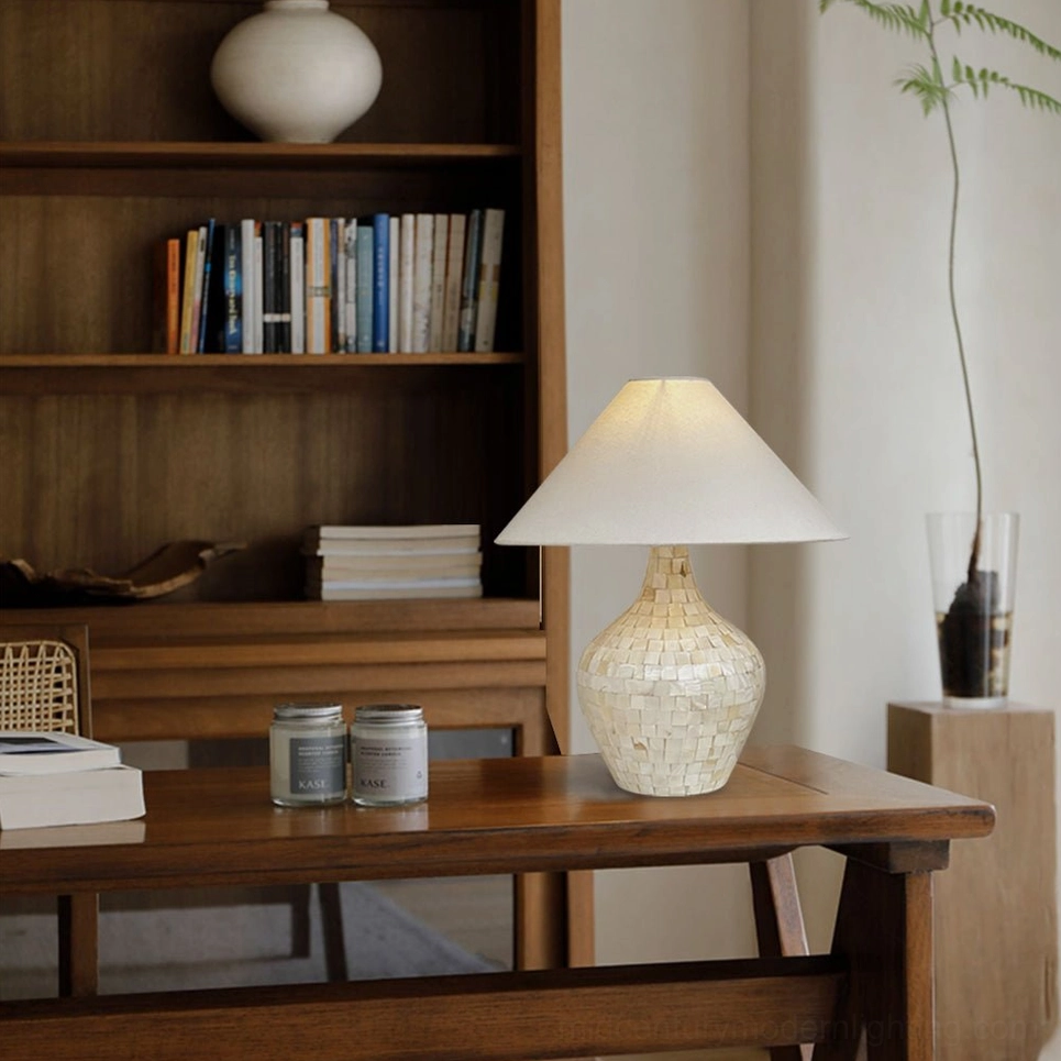 Shell inlay table lamp beside home office bookshelf and storage jars on wooden desk, study room lighting