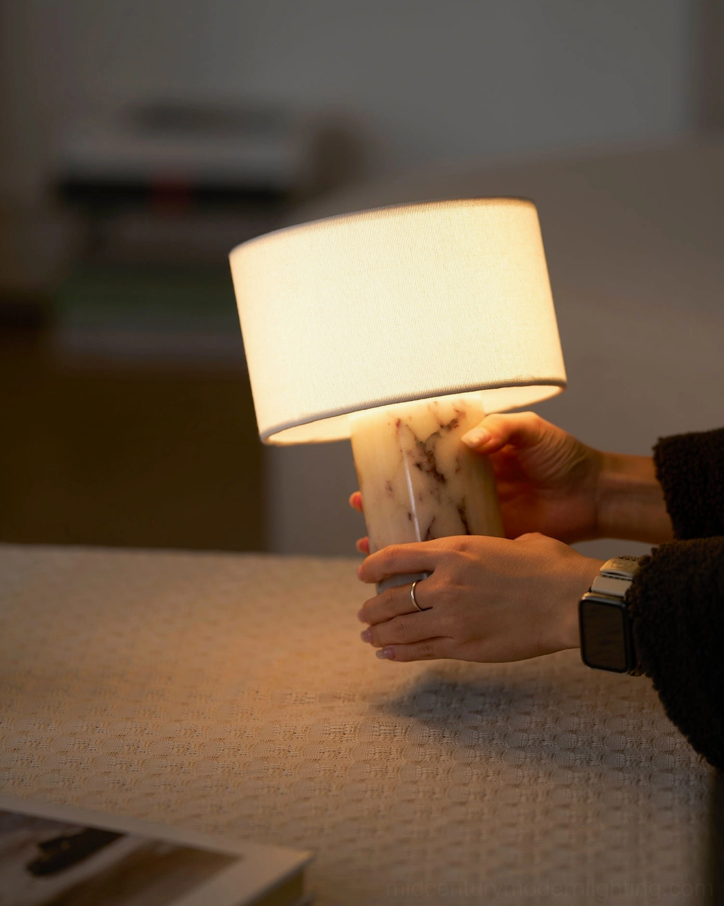 Hand holding Sediment marble lamp base demonstrating portable cordless design and weight