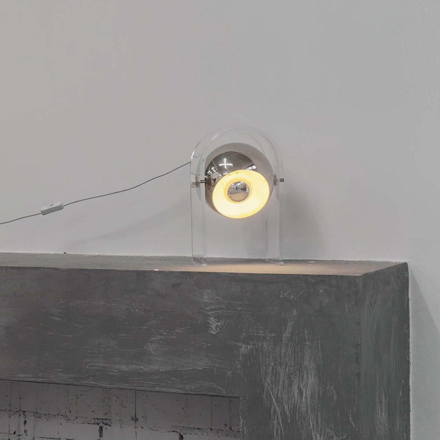 Modern acrylic lamp on concrete ledge with industrial minimalist aesthetic and gray wall