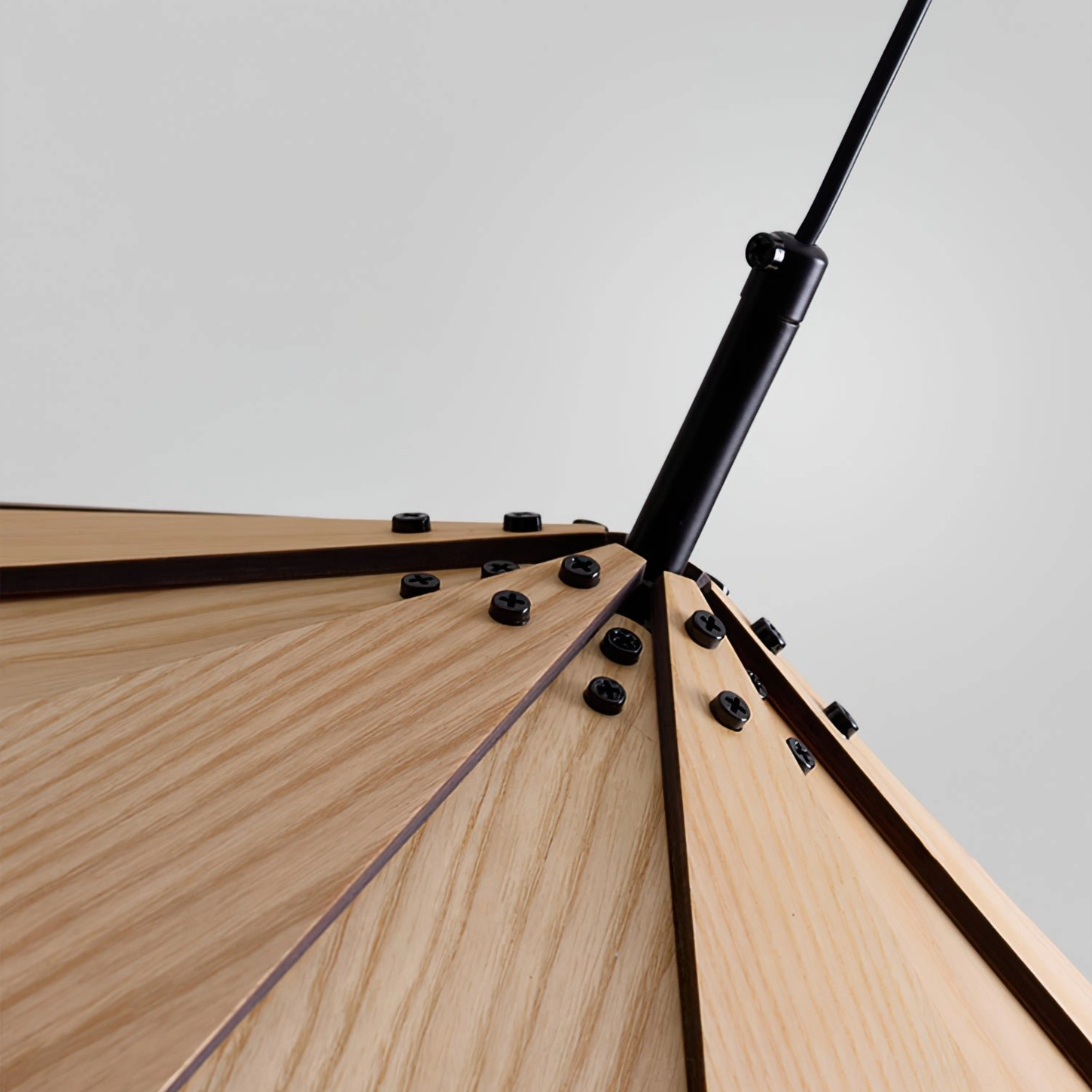 Low-angle close-up of sepal lamp wooden joint detail revealing oak grain and black metal hardware