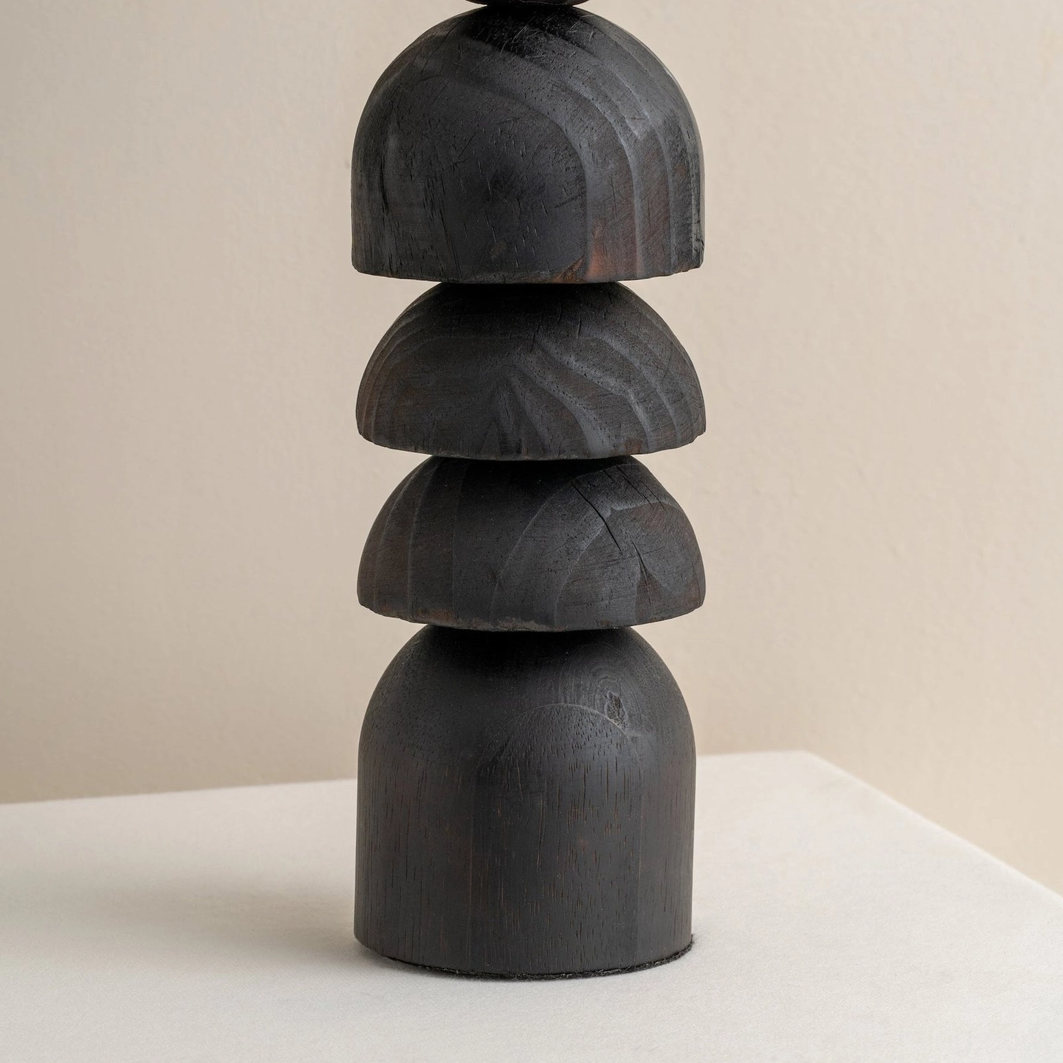 Sculptural blackened wood stacked base of Sergio lamp isolated on white background