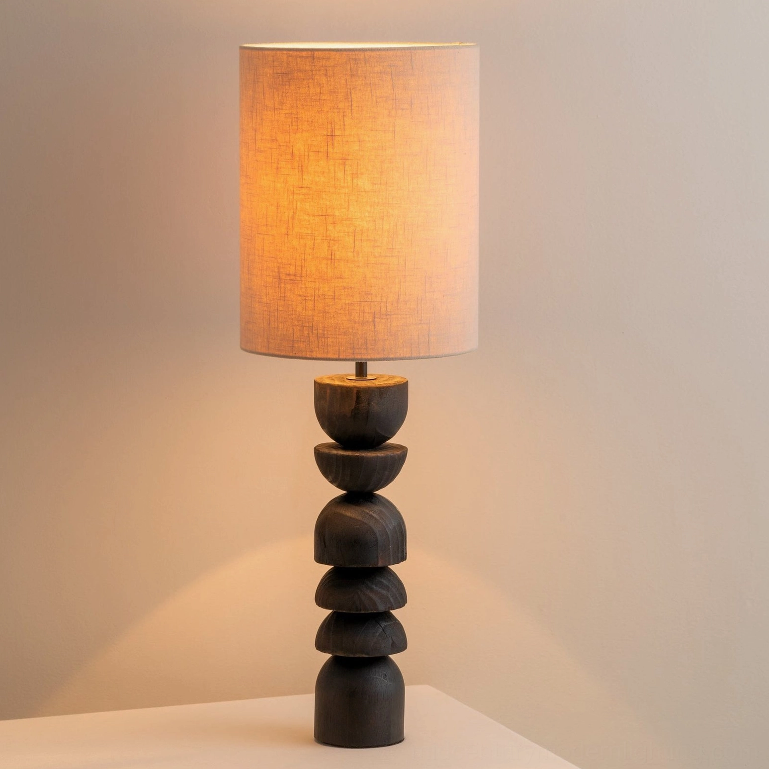 Illuminated Sergio lamp with warm ambient light glowing through beige linen shade