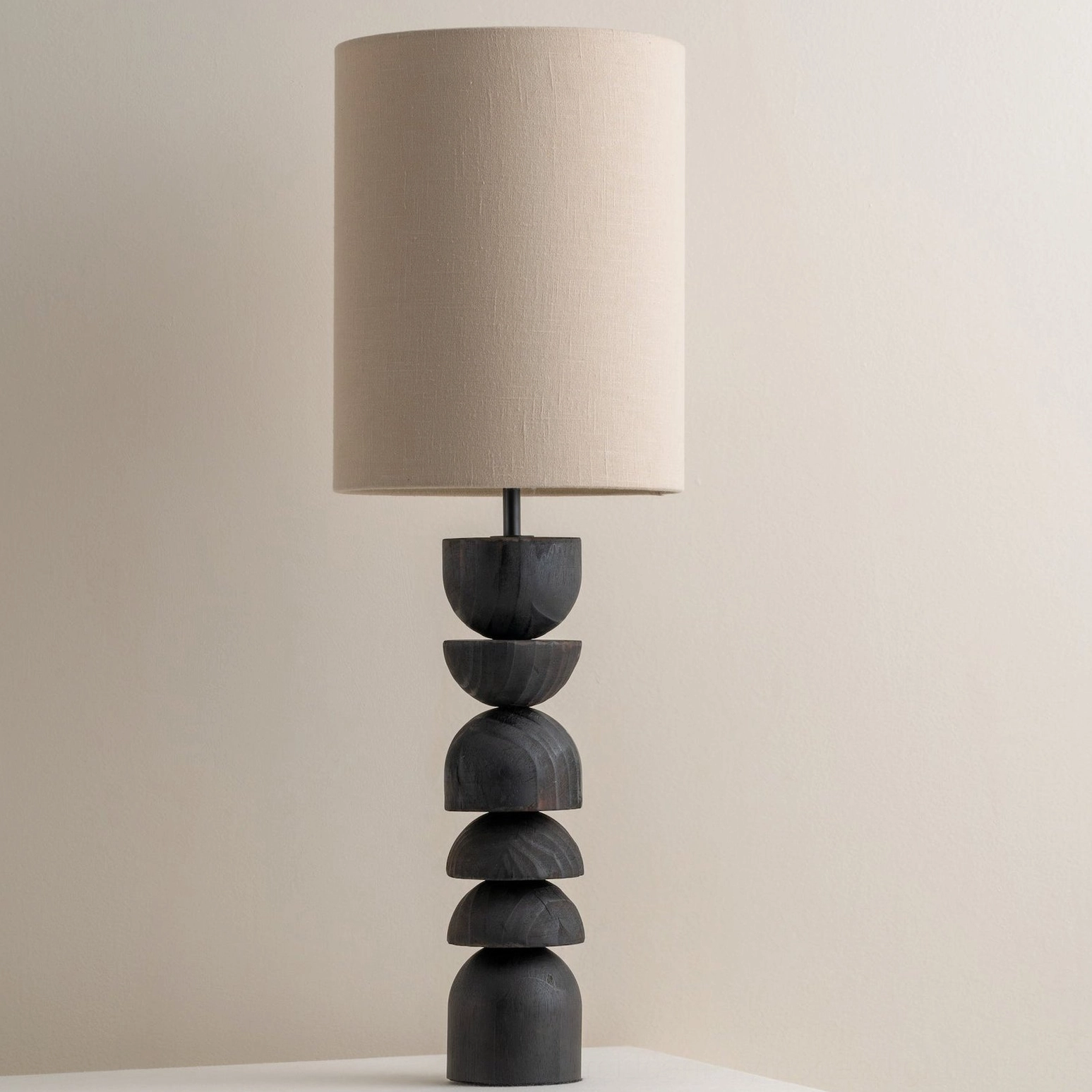 Sergio minimalist table lamp with tall stacked dark wood base and neutral fabric shade