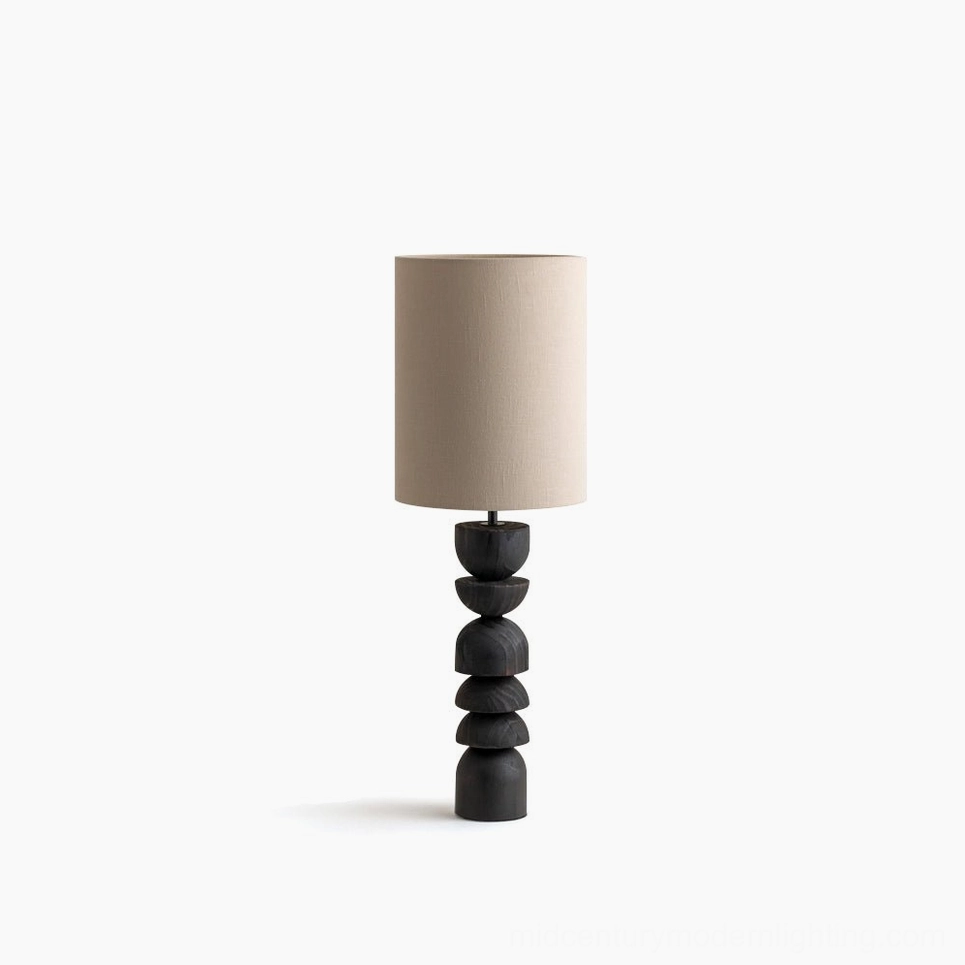 Sergio sculptural table lamp with stacked blackened wood base and beige linen shade on white background