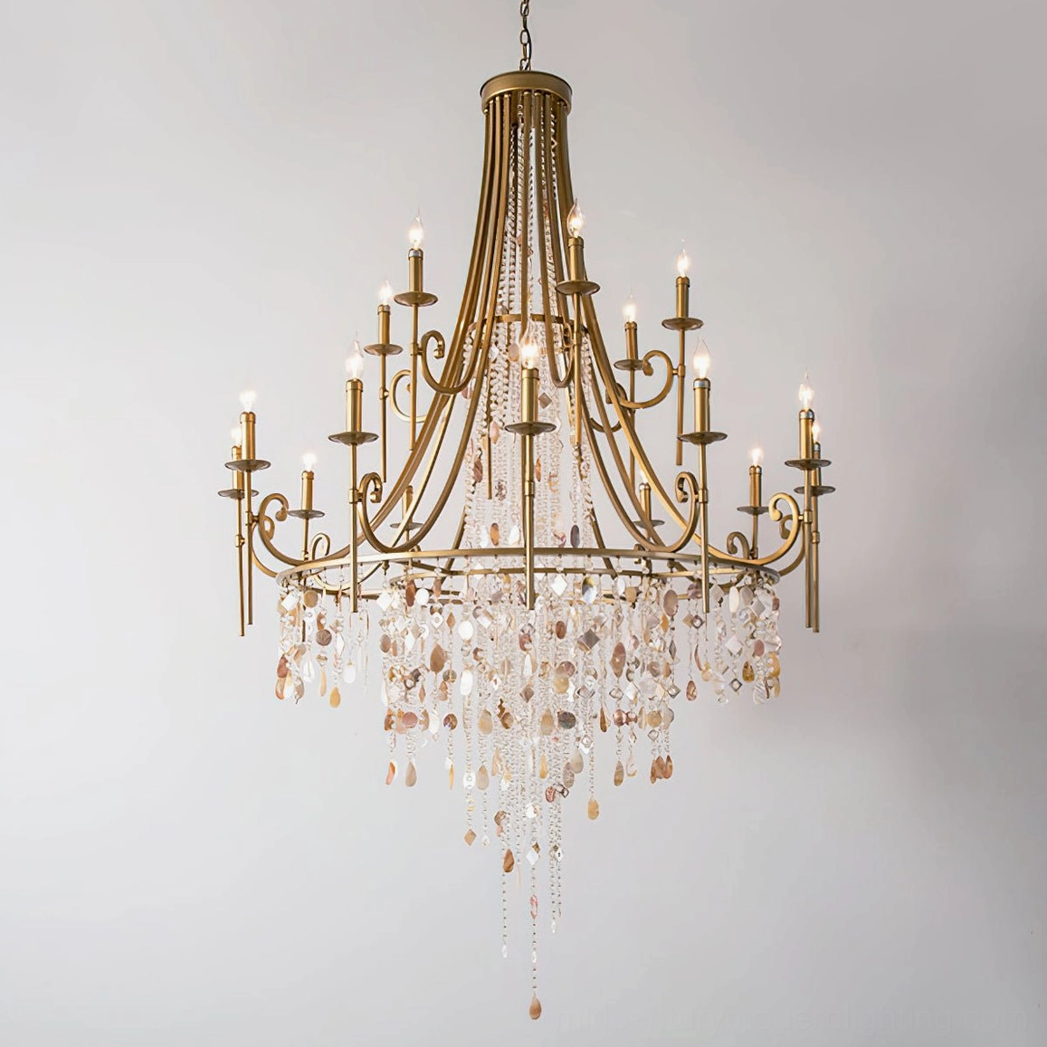 Brass crystal shell chandelier frontal full view displaying tiered structure with bright illuminated candle tops