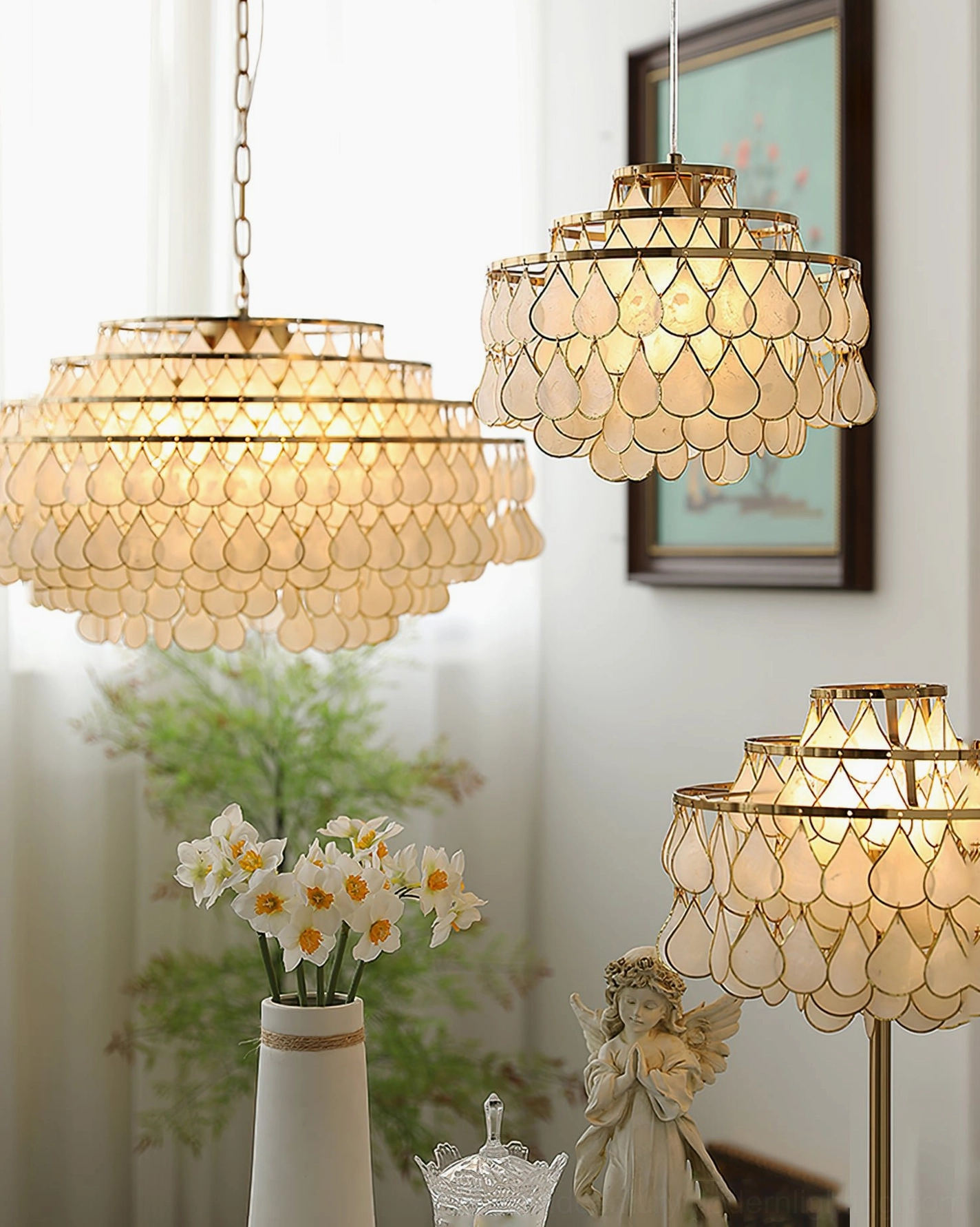 Matching shell pendant and floor lamps in cozy home corner, three-quarter side view with framed art, decorative statue and floral vase, gold hardware