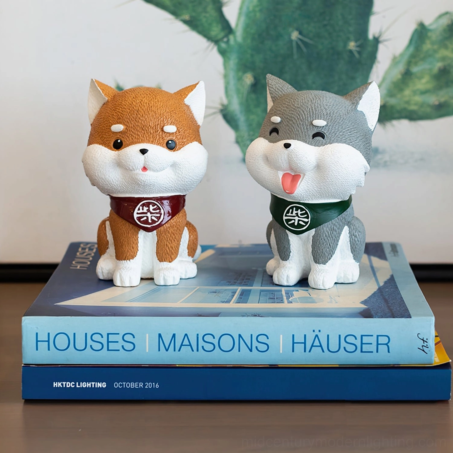 Two decorative Shiba Inu figurines with scarves displayed on stacked books tabletop