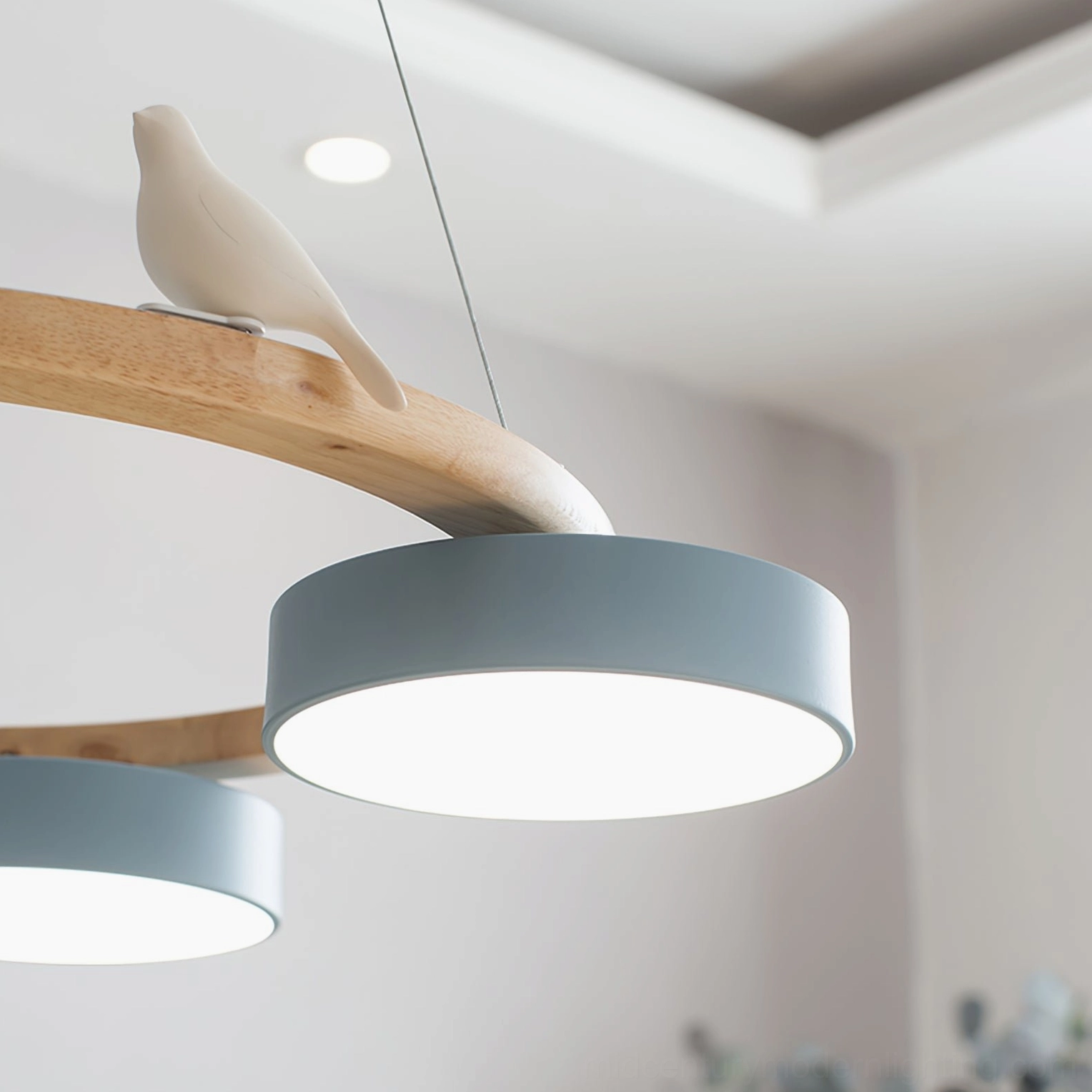 Close-up detail of Sienna bird pendant light showing gray-blue frosted acrylic shade, ceramic white bird ornament, and natural wood branch frame