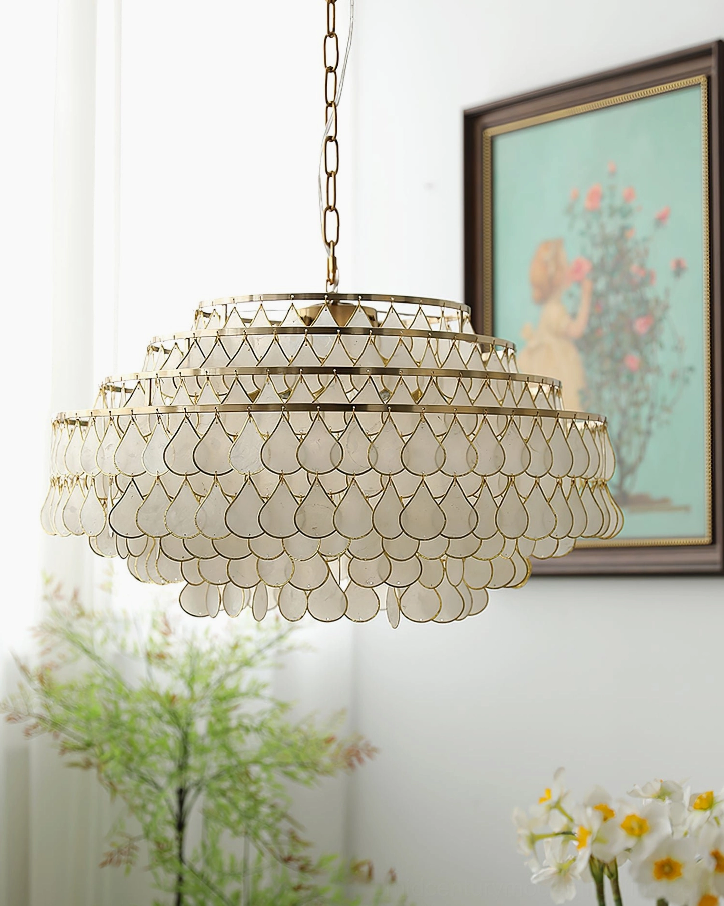 Single tiered shell pendant lamp front three-quarter view, indoor space with framed wall art, green plants and table flowers, romantic French vintage