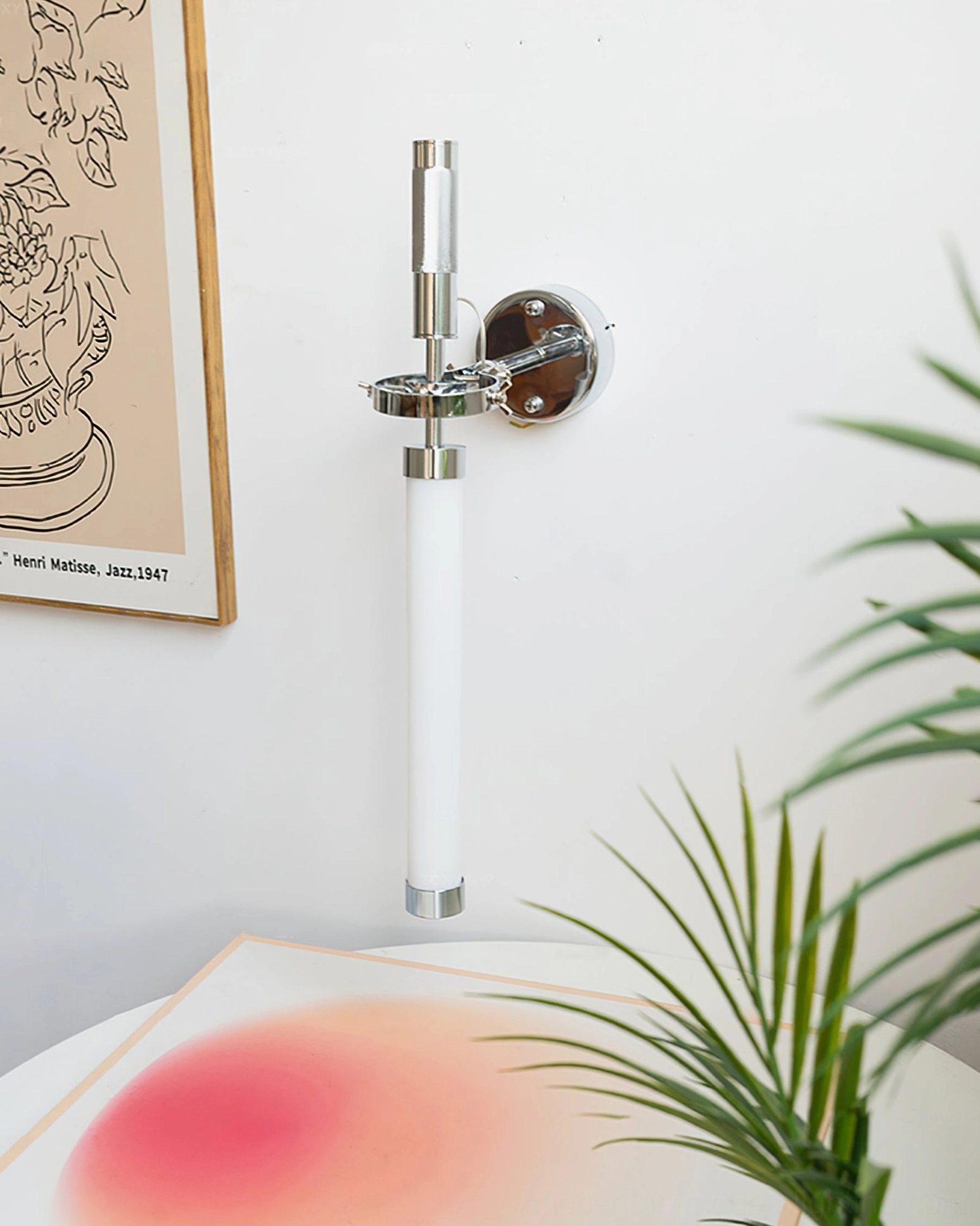Contemporary chrome wall sconce with frosted glass tube, angled tabletop styling view