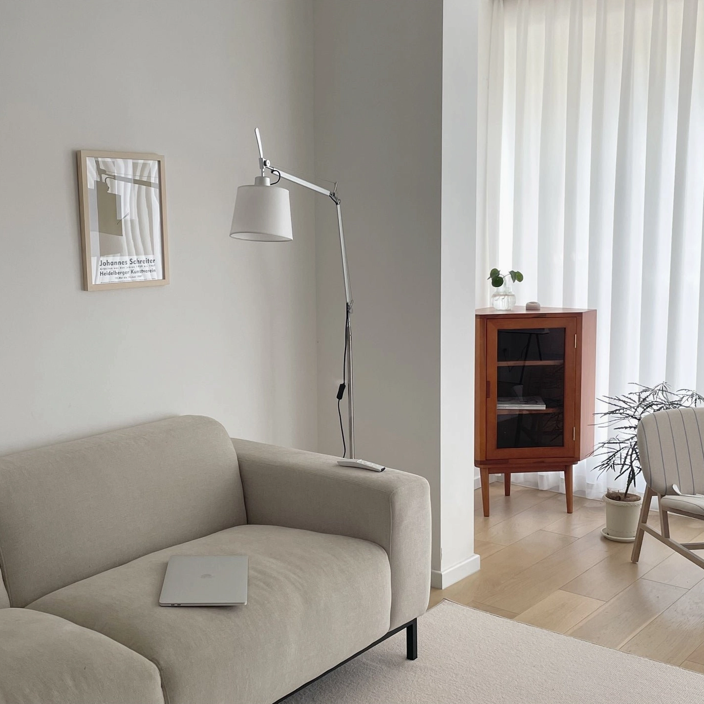 Slim articulating floor lamp with light gray fabric shade in minimalist living space, refined silver metalwork