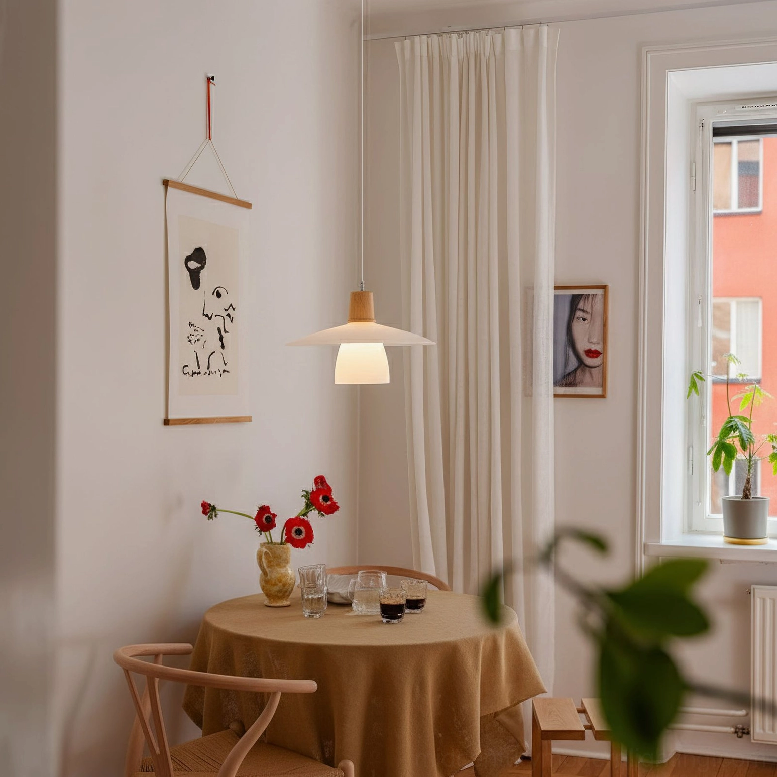 Small decorative minimalist pendant light with off-white shade and wood top in cozy round dining corner