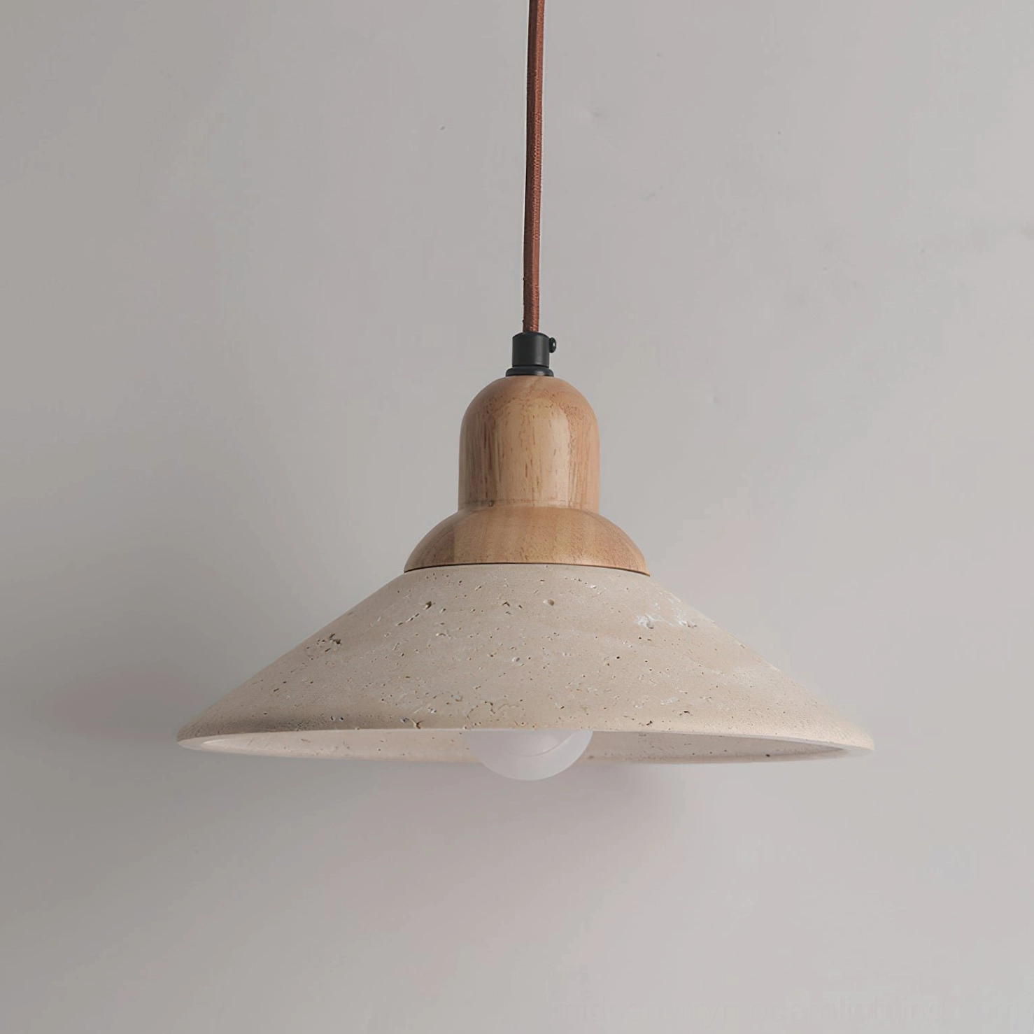 Close-up detail of Solara pendant showing travertine stone texture, wood joint, and brown fabric cord