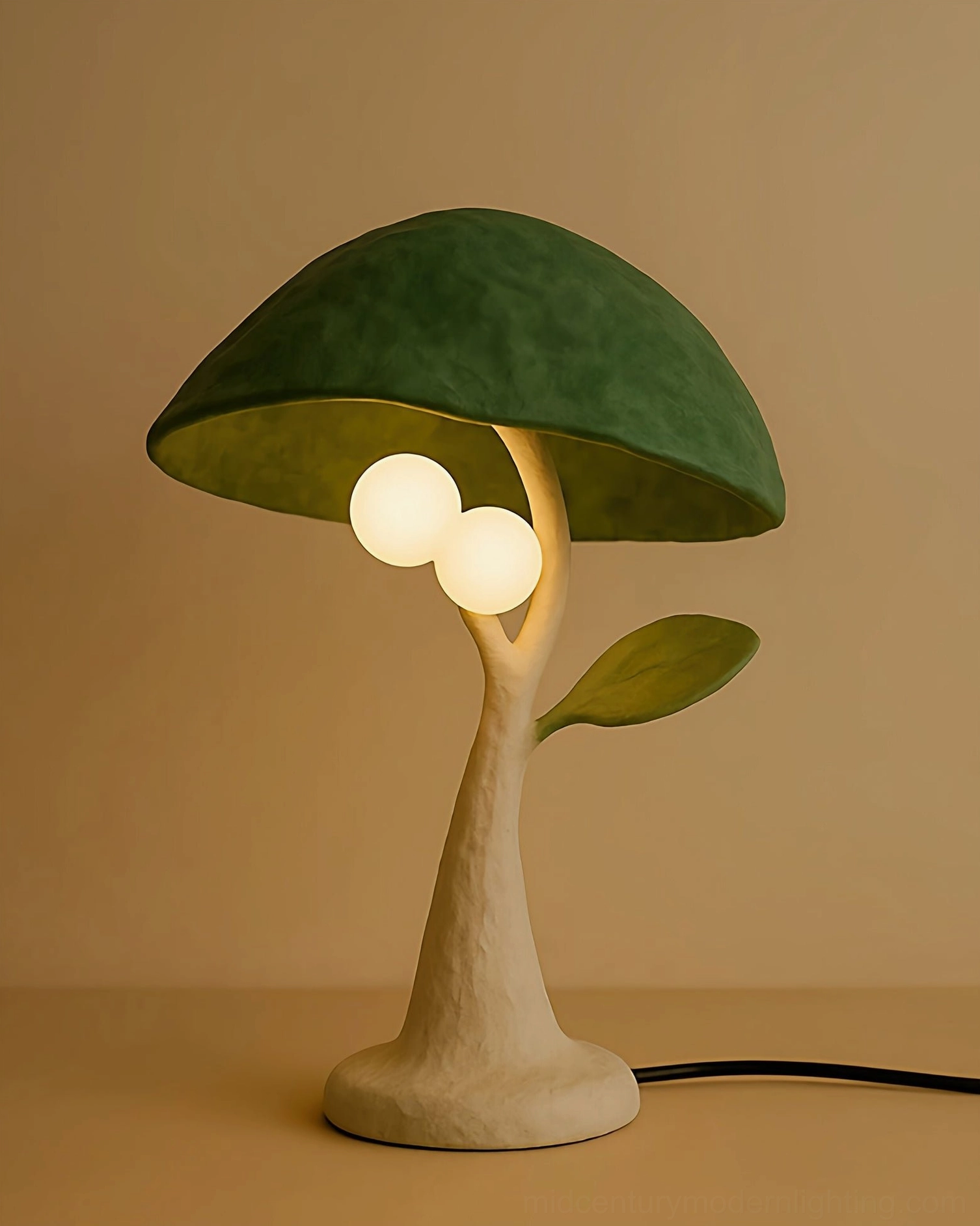 Close-up three-quarter view of Soloma sculptural resin lamp with matte green asymmetrical canopy, frosted glass diffusers, and sculpted side leaf detail against warm backdrop