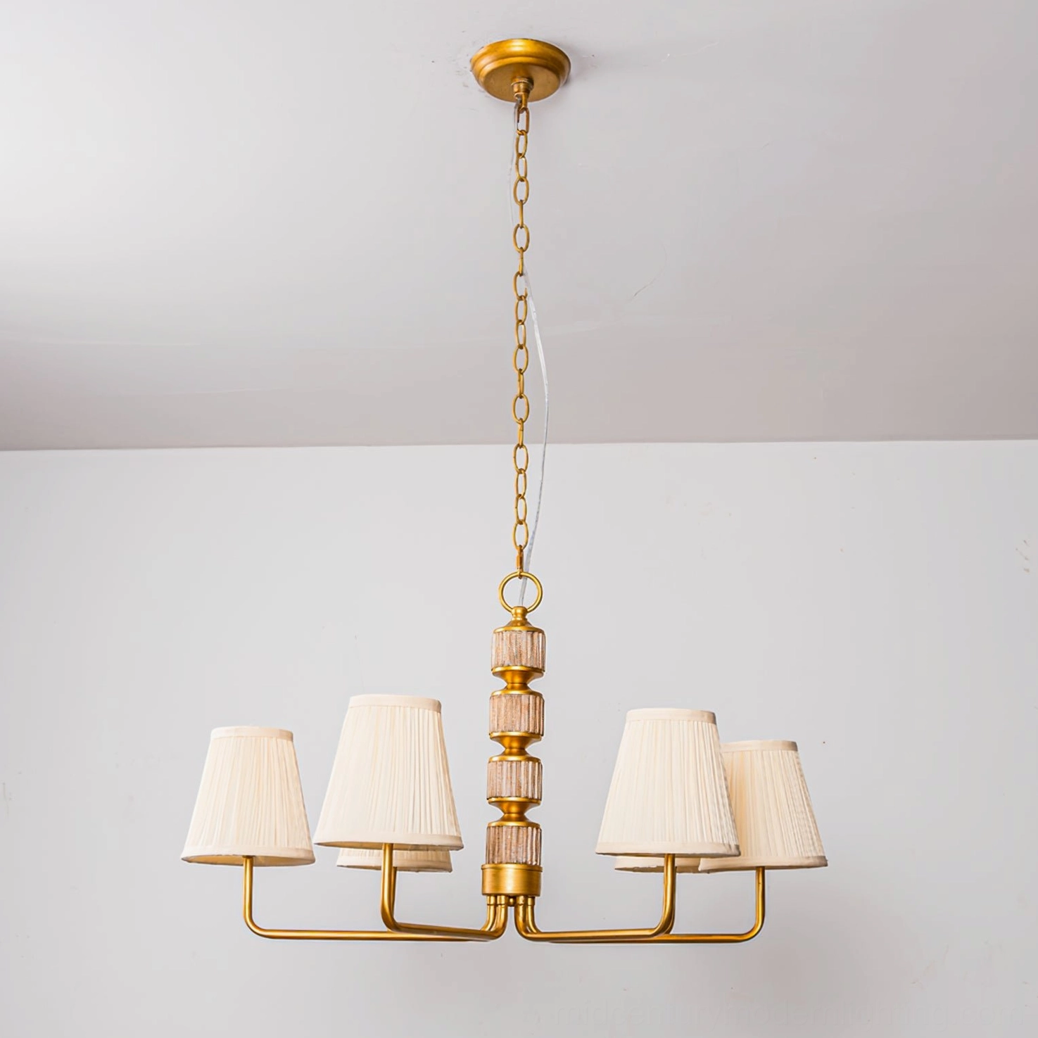 4-arm brass gold finished Stacey chandelier side overhead view with golden stacked wooden central post and pleated shades