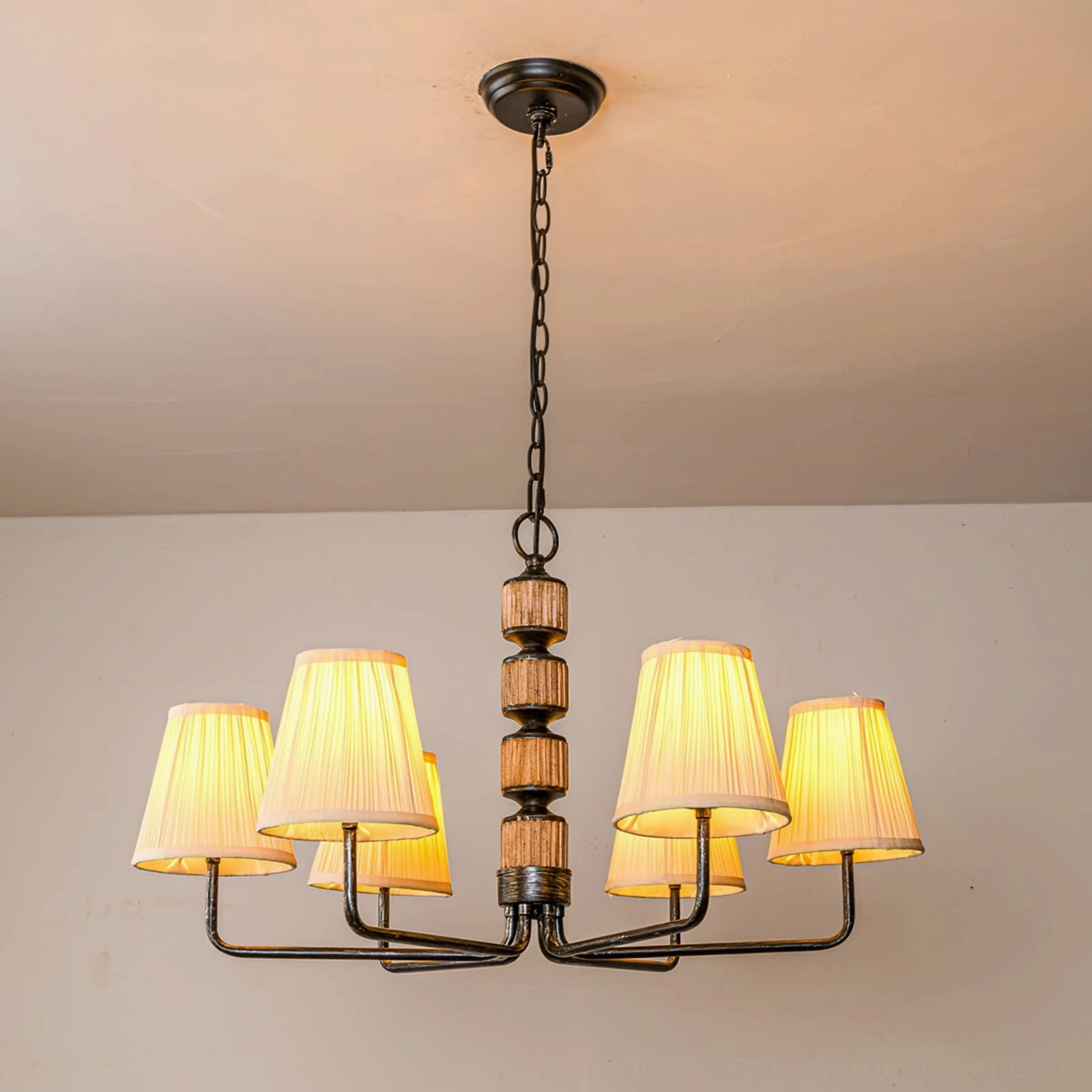 6-arm black Stacey chandelier front overhead full view with illuminated pleated shades showing warm light diffusion