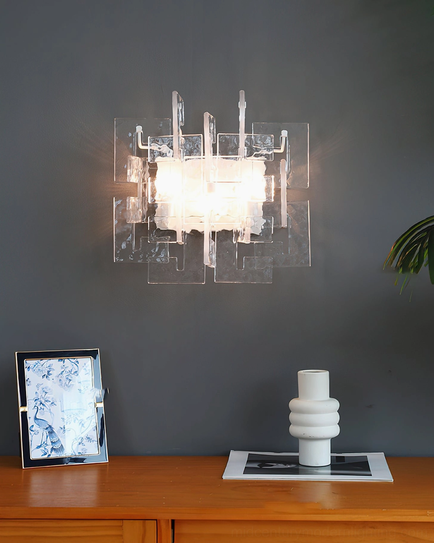 Stagger cast glass wall sconce clear glass in home entryway wooden console table warm lighting