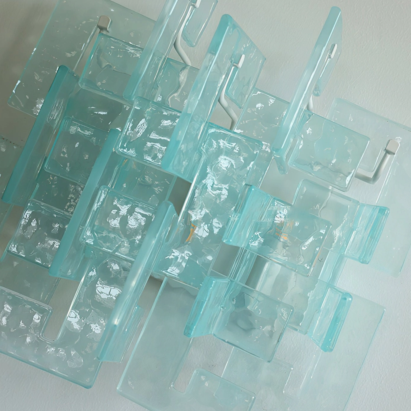 Close-up detail of stagger cast glass sconce textured rippled panels metal mounting bracket