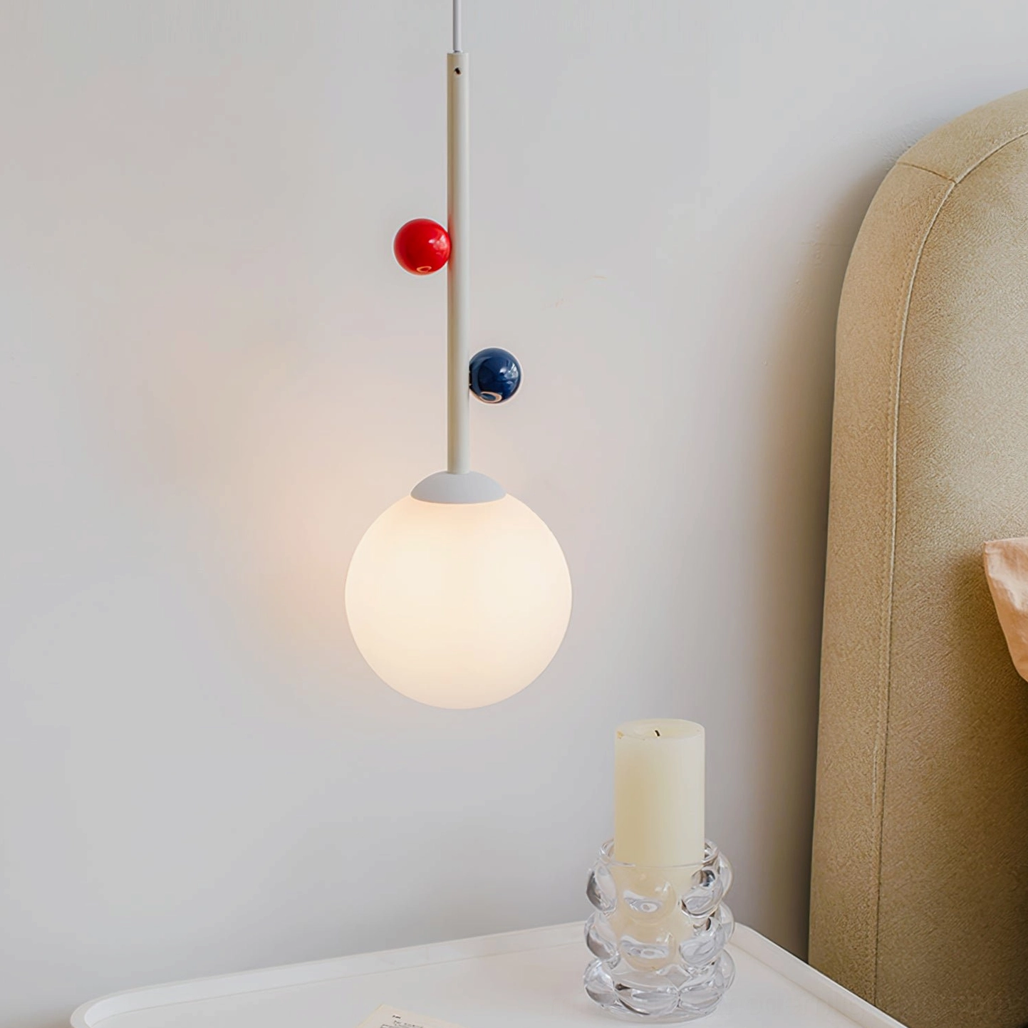 Stax pendant lamp illuminated beside white nightstand with decorative glass candle, side perspective