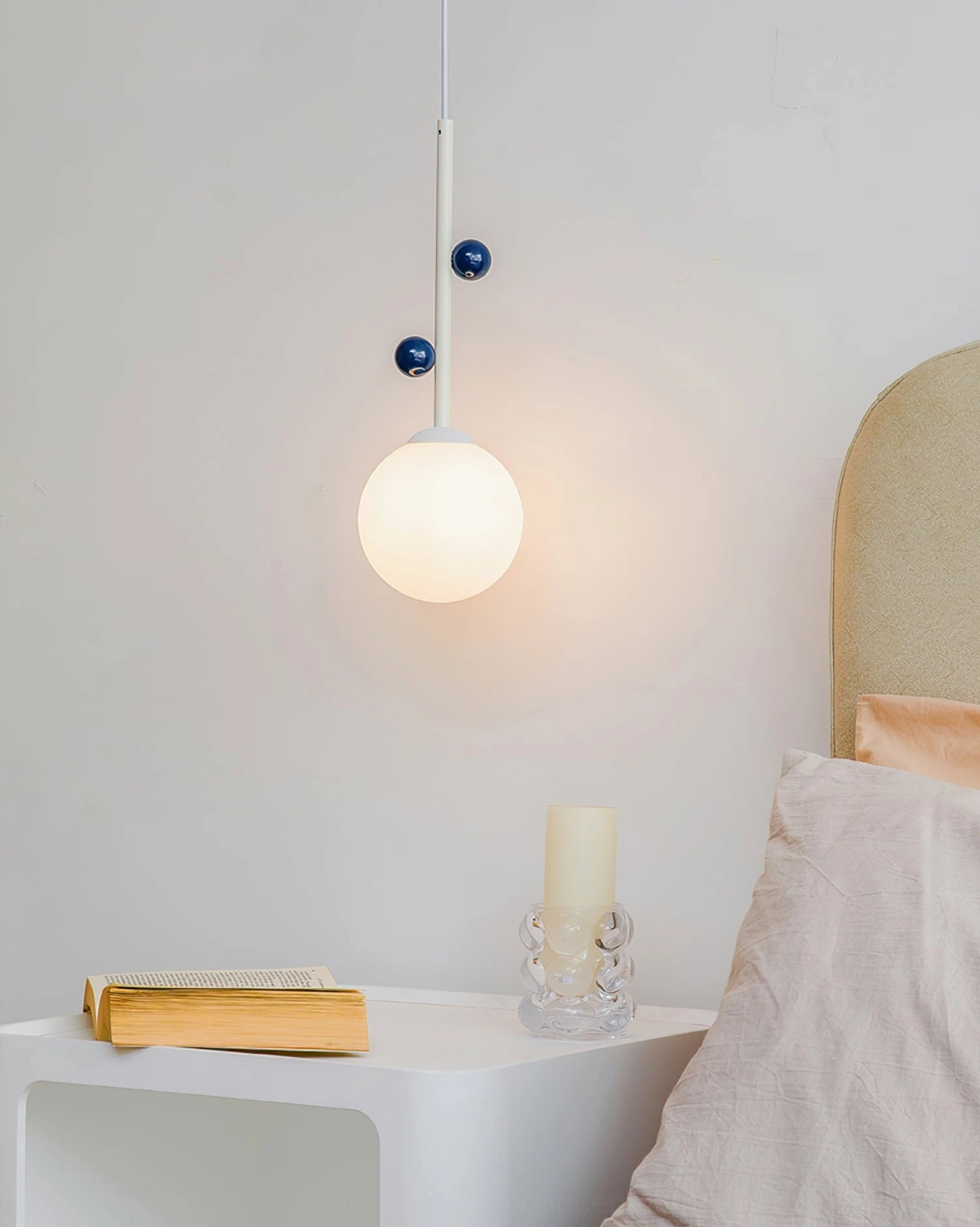 Lit Stax bedside pendant lamp creating warm ambient glow in bedroom setting, close-up detail view