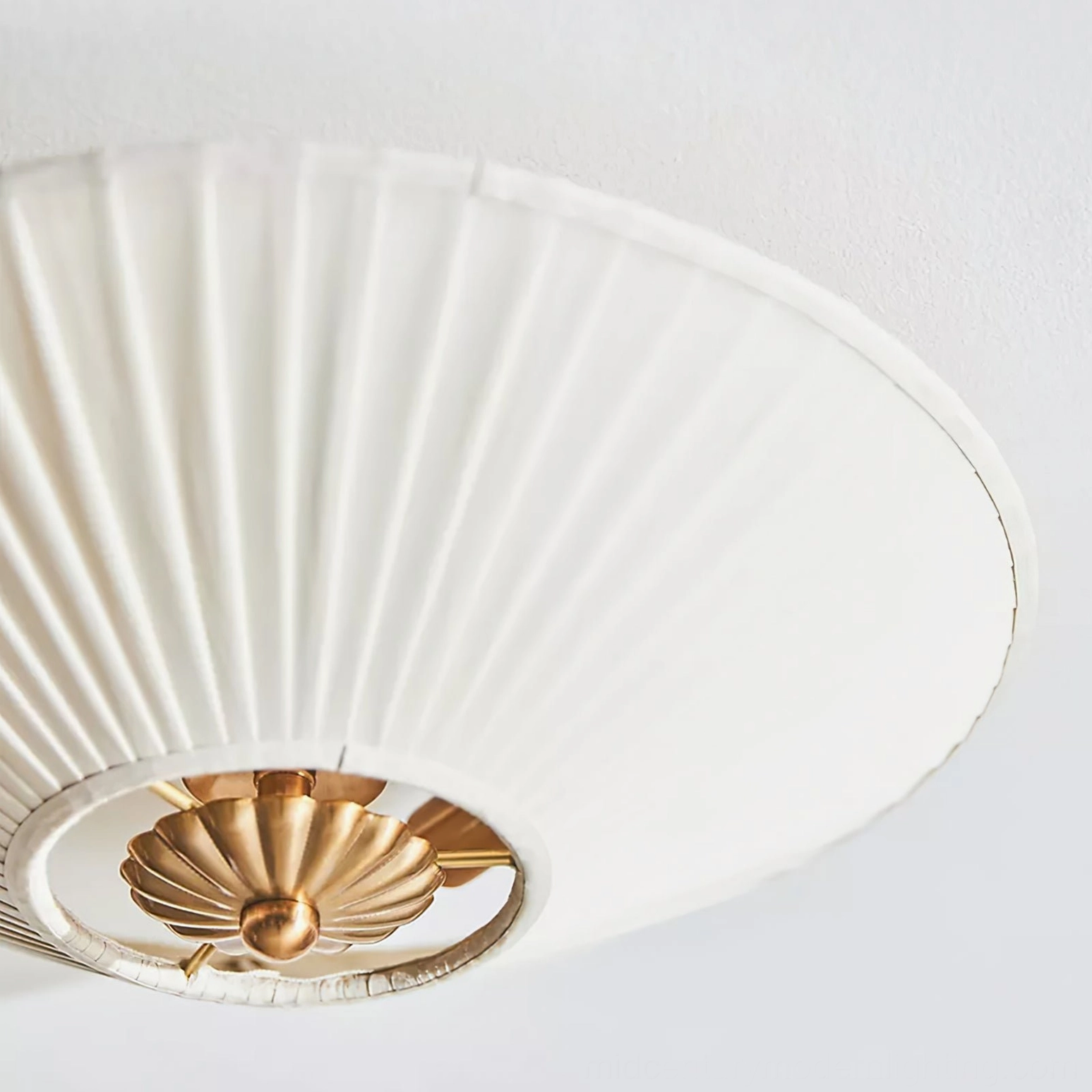 Close-up detail of Stefanie lamp showing ornate scalloped brass base and tight vertical fabric pleats