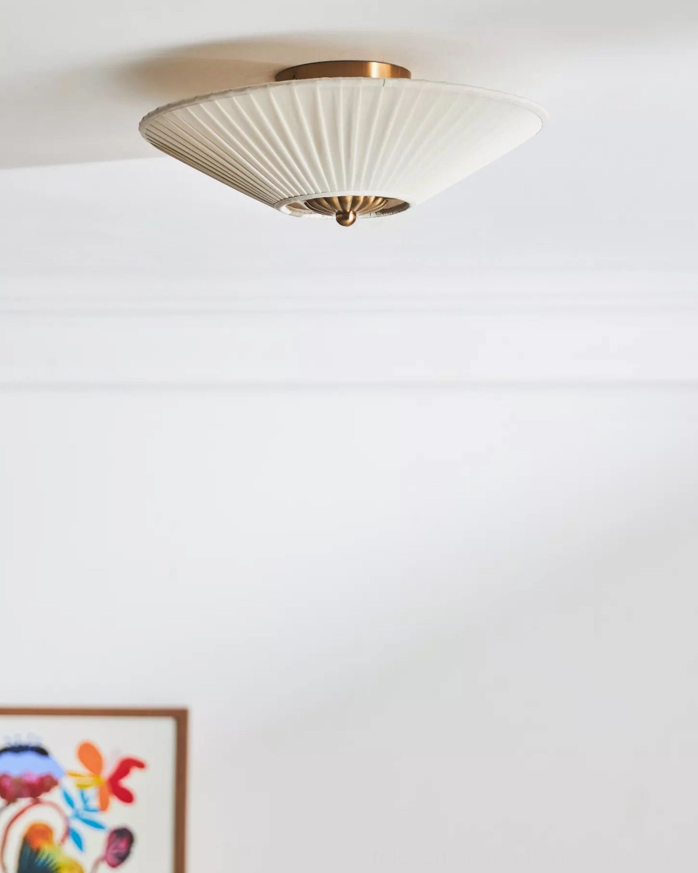 Stefanie mid-century modern pleated ceiling lamp with narrow conical shade and brass gold hardware beside framed artwork