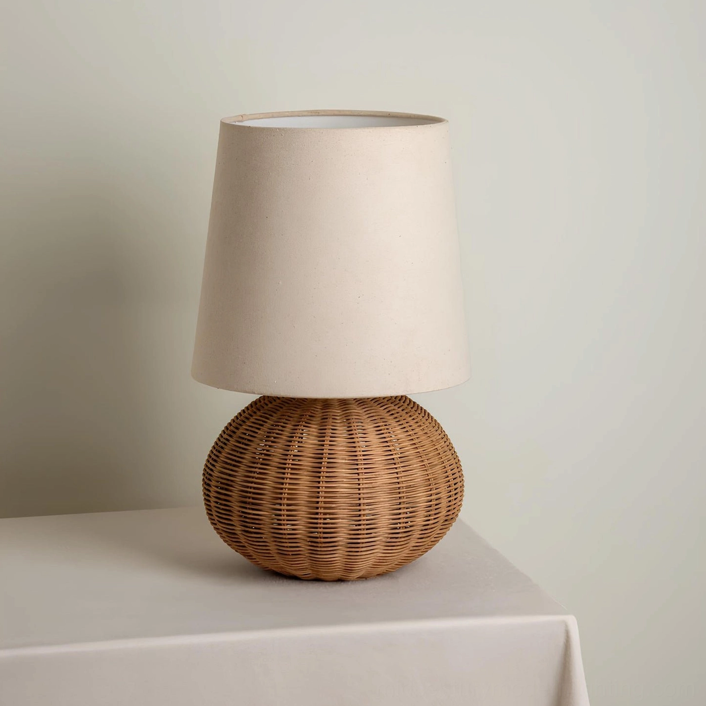 Compact Stellan rattan table lamp with petite proportions, side view on minimal studio background
