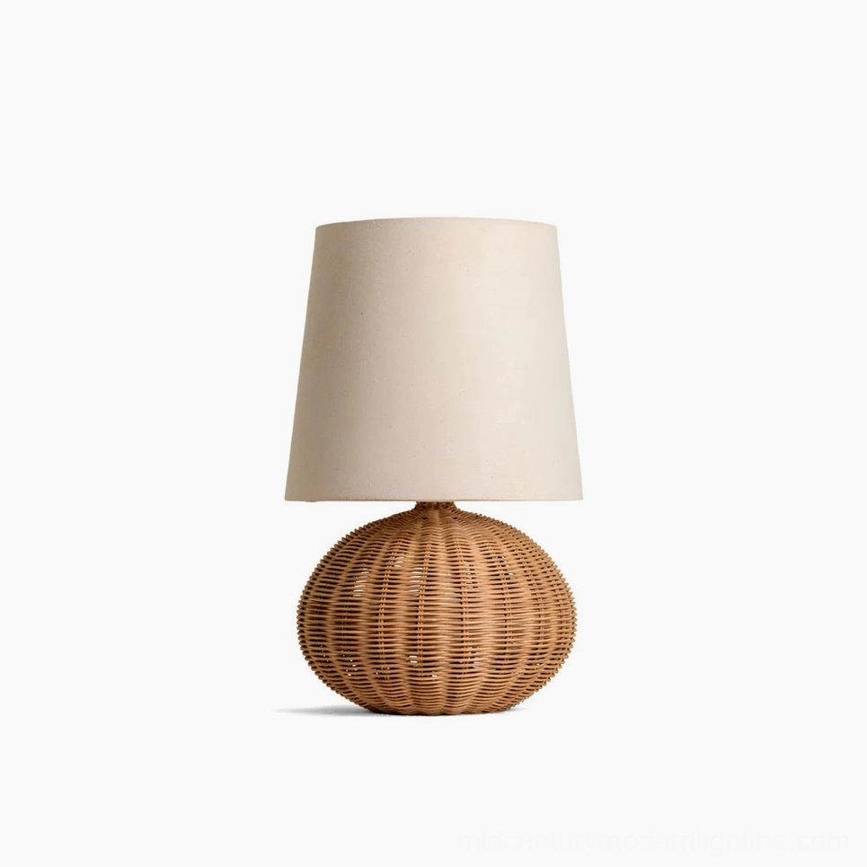 Stellan rattan table lamp with spherical handwoven base and neutral linen fabric shade, front studio view