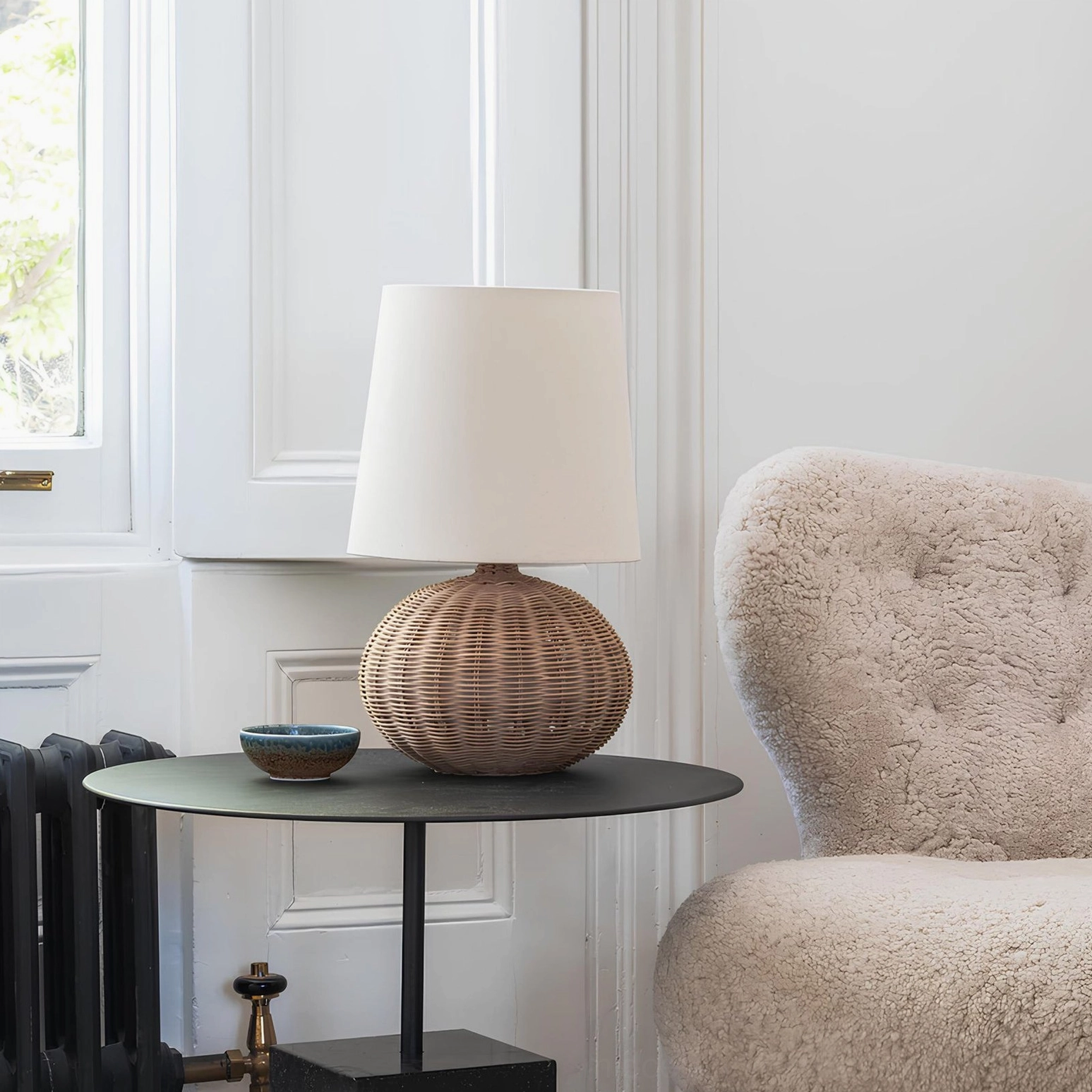 Stellan rattan lamp with spherical base displayed on small side table in minimalist living room near window