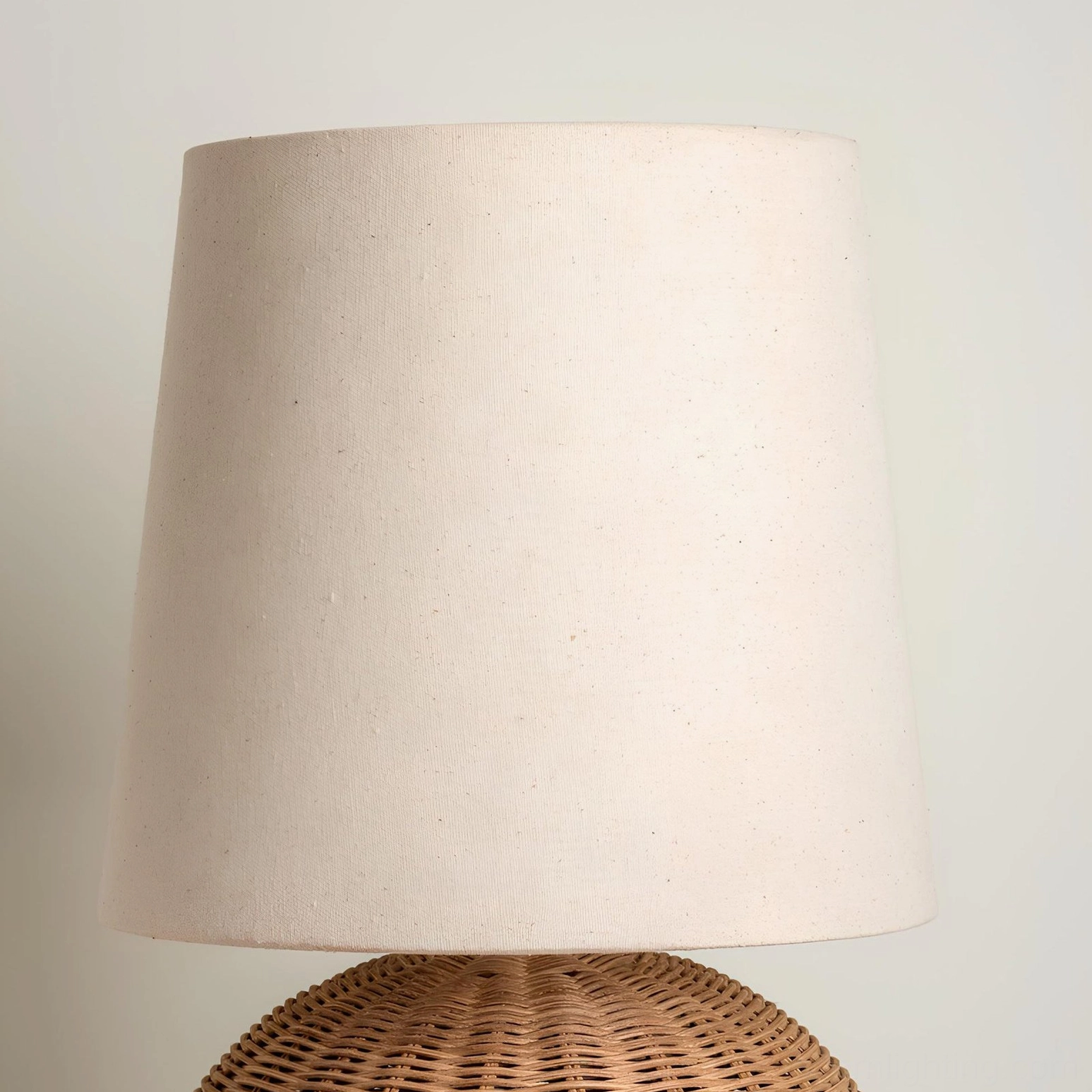 Top-down close-up of Stellan rattan table lamp shade and partial base, showing smooth fabric and natural weave
