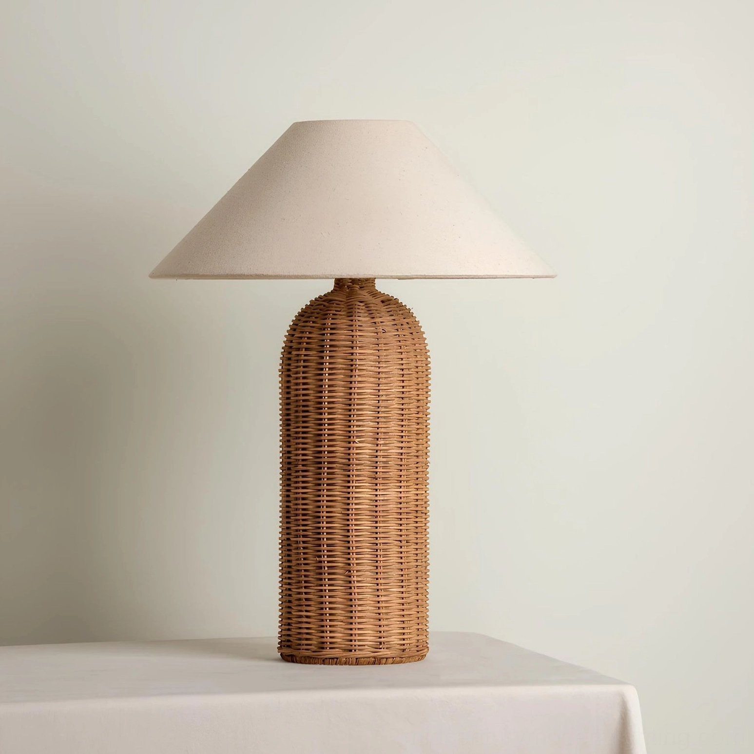 Stellan rattan table lamp with warm linen shade diffusing soft light in contemporary home environment