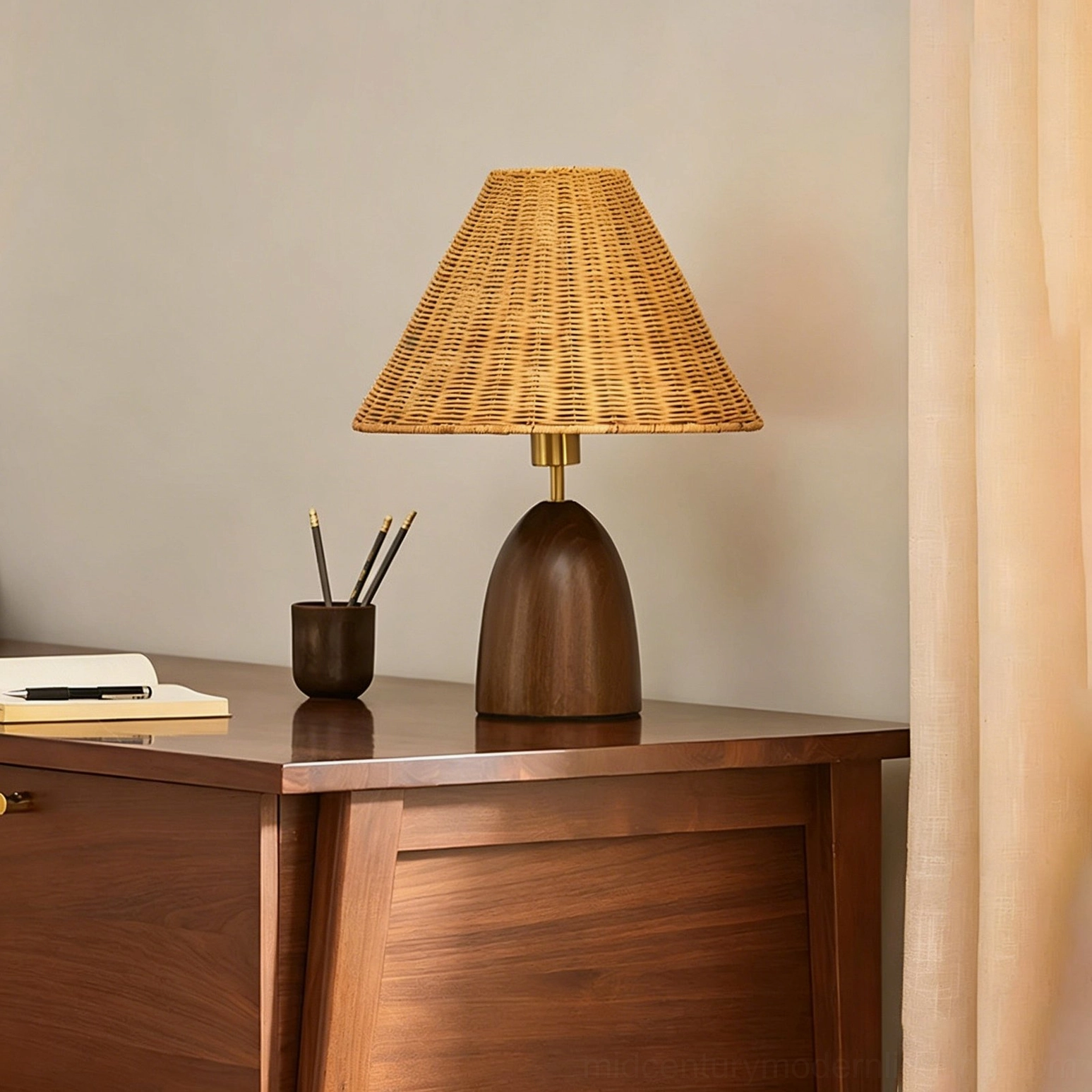 Suri rattan table lamp on home office wooden desk beside stationery holder, side three-quarter view showing woven shade detail