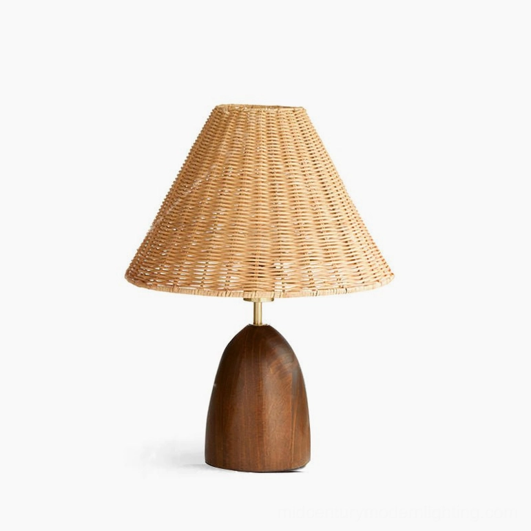 Suri rattan table lamp close-up frontal view on dark wood desk background, illuminated bulb visible with pen holder, detail shot