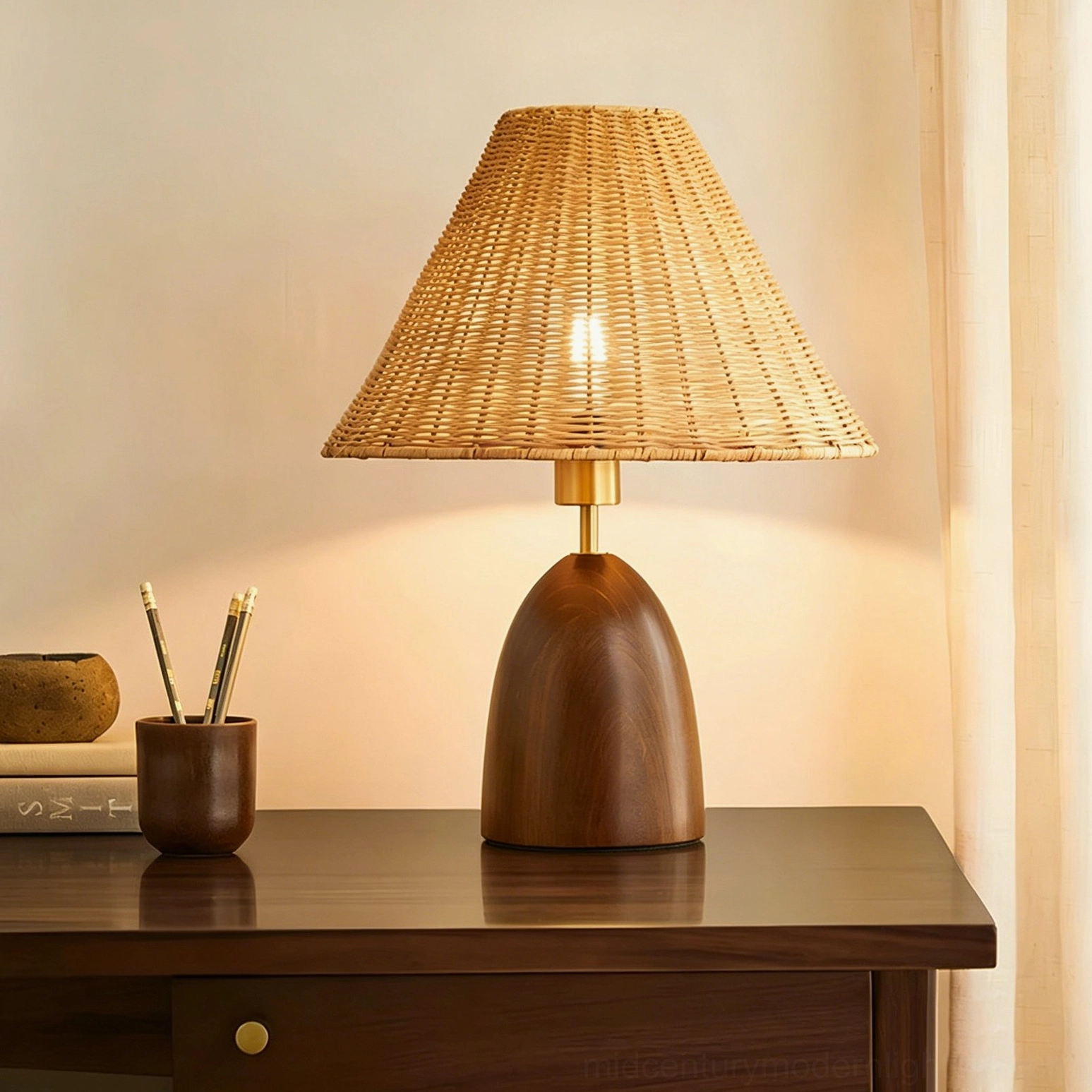 Suri rattan lamp illuminated on study desk with pen holder, front view showing warm bulb glow through woven rattan shade