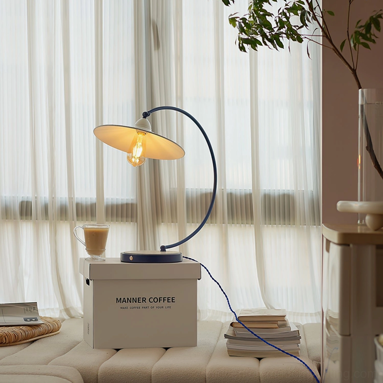 Swan Blue Table Lamp beside modern living room sofa - three-quarter front view on coffee table