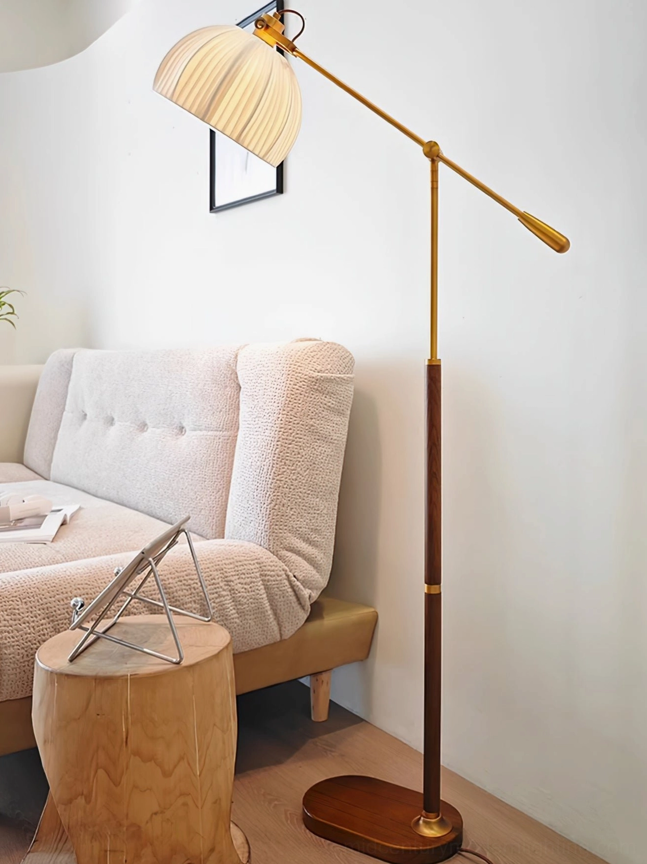 Swing arm pleated floor lamp with dark oval metal base in nordic minimalist style positioned beside small cozy tufted sofa