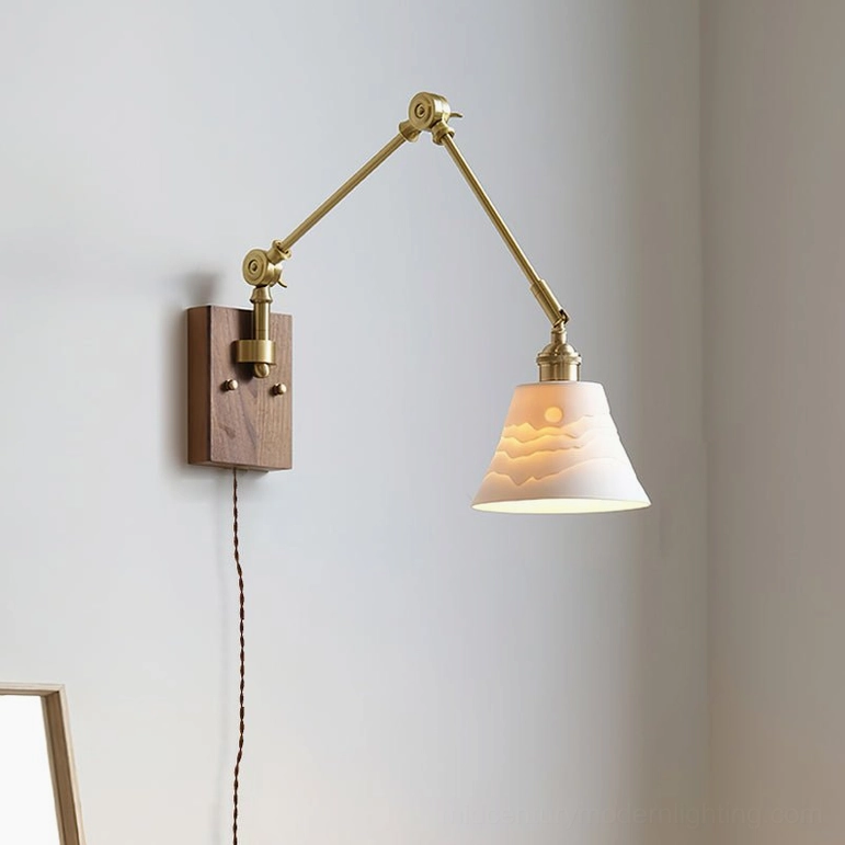 Swing arm wall lamp featuring embossed landscape pattern on ceramic shade and brass arm