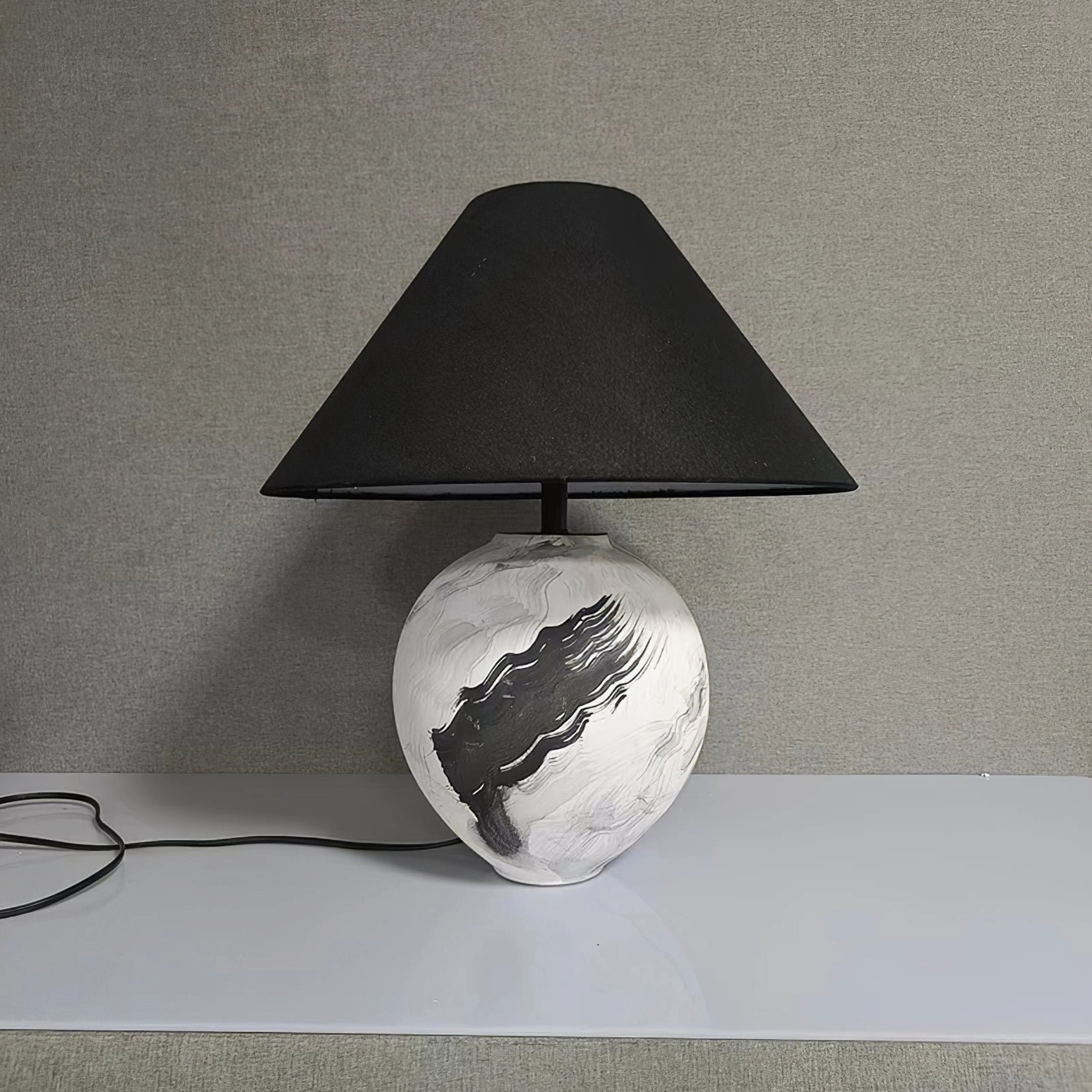 Modern table lamp with power cord displayed on minimalist wall background, side profile view
