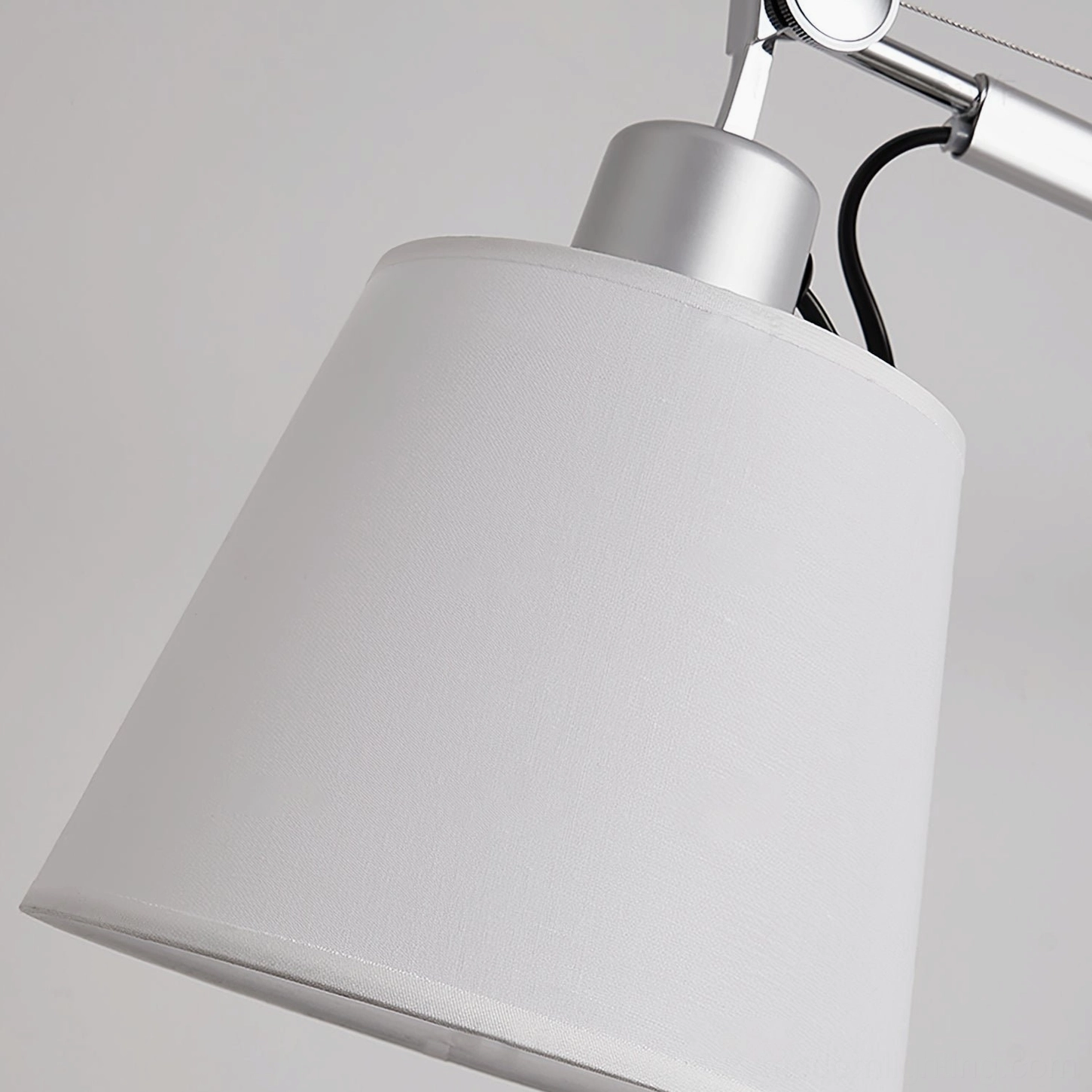 Close-up detail of adjustable table lamp shade and upper arm joint mechanism, highlighting fabric texture and metal hardware