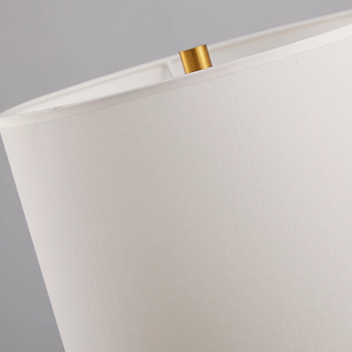 Close-up detail of white woven fabric lampshade with gold metal finial accent on Sauce table lamp