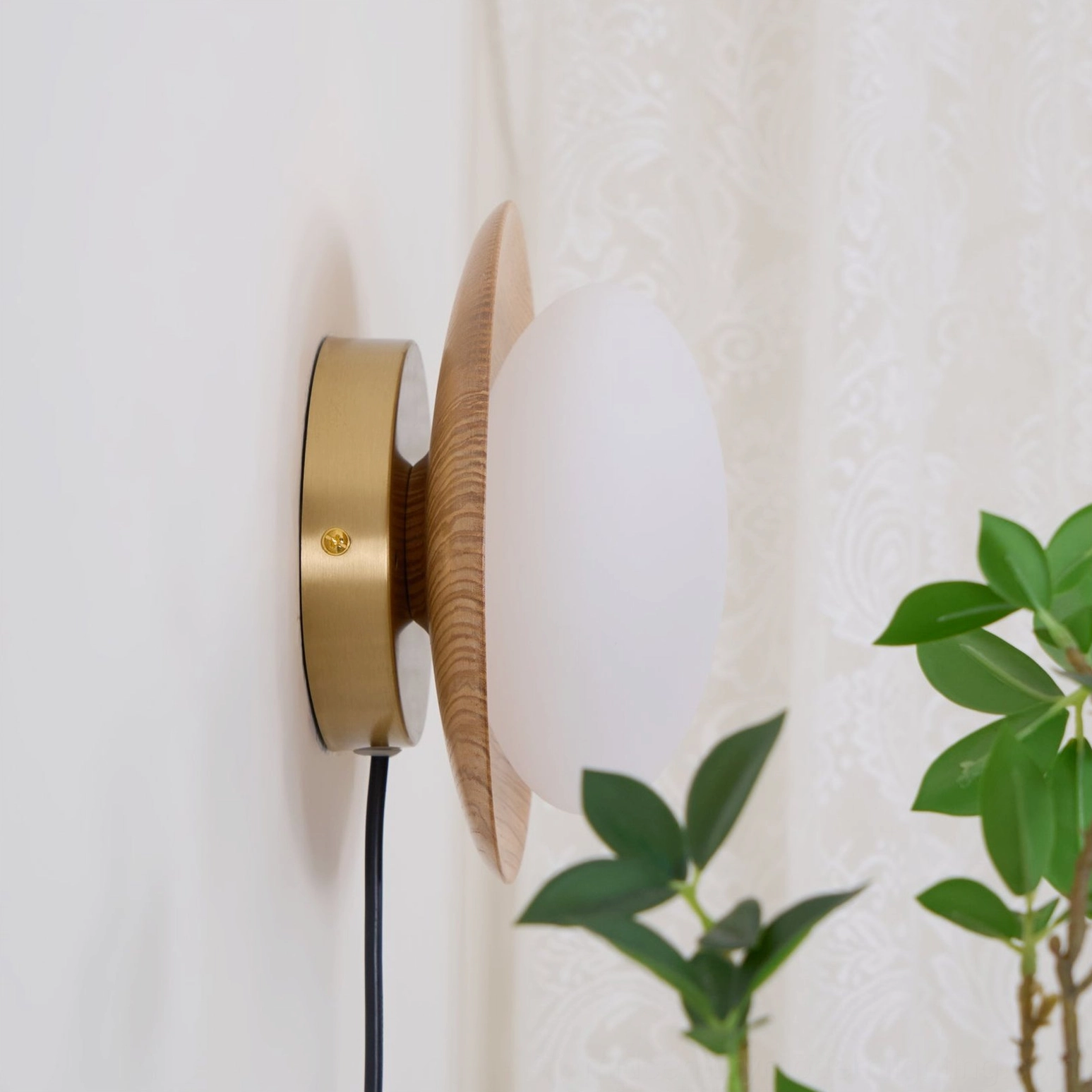 Tablet plug-in lamp side profile displaying compact wooden trim and integrated LED globe against green foliage backdrop