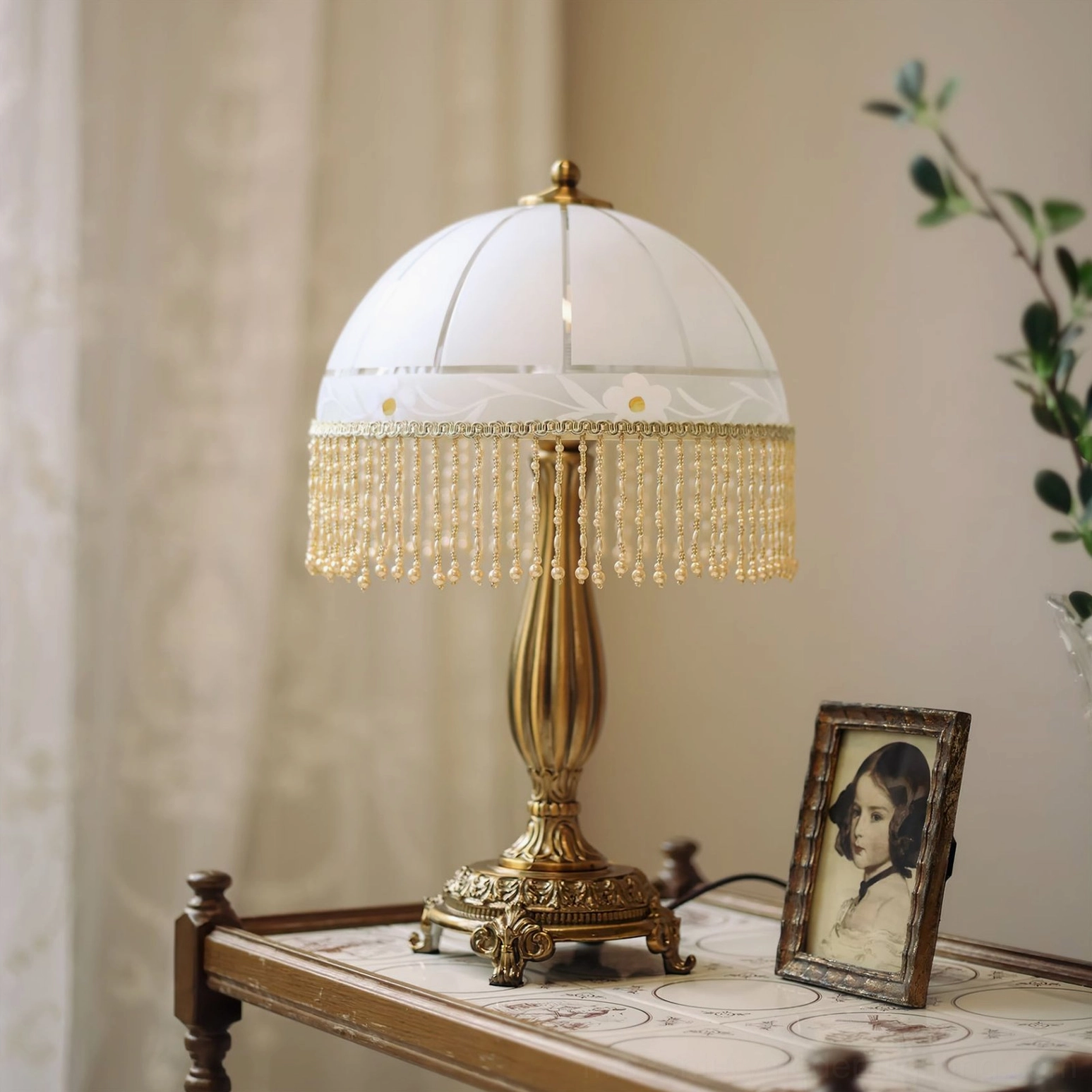 Vintage tassel flower lamp as bedroom nightstand accessory with framed portrait and sheer curtain backdrop