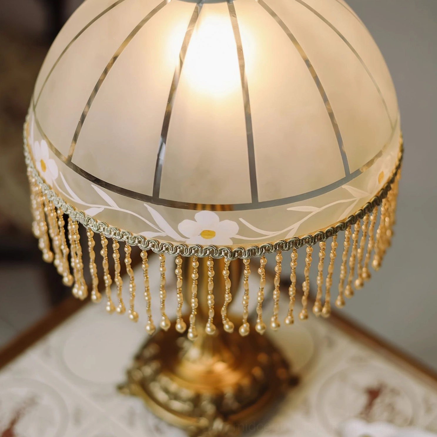 Extreme close-up of frosted glass dome with printed floral pattern and hanging decorative beaded tassel trim